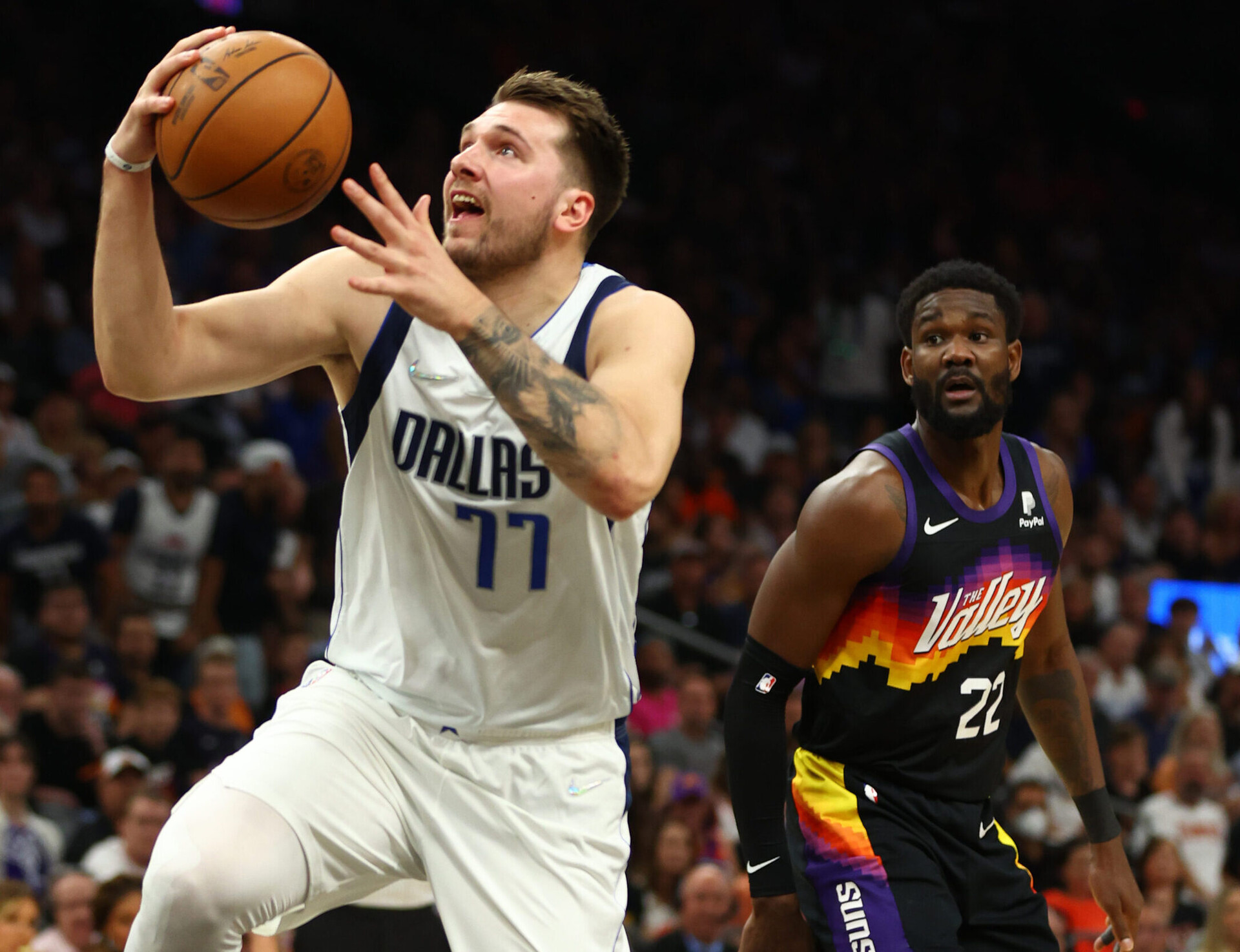 Dallas Mavericks guard Luka Doncic, left, goes up for a basket with his right hand as Phoenix Suns center Deandre Ayton, right, looks on May 15, 2022, in Phoenix.