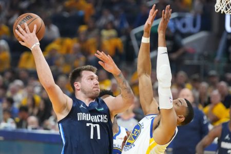 Dallas Mavericks guard Luka Doncic, left, throws a no-look pass behind his back with his right hand while being guarded by Golden State Warriors forward Otto Porter Jr., right with hands in the air, on Friday, May 20, 2022, in San Francisco.