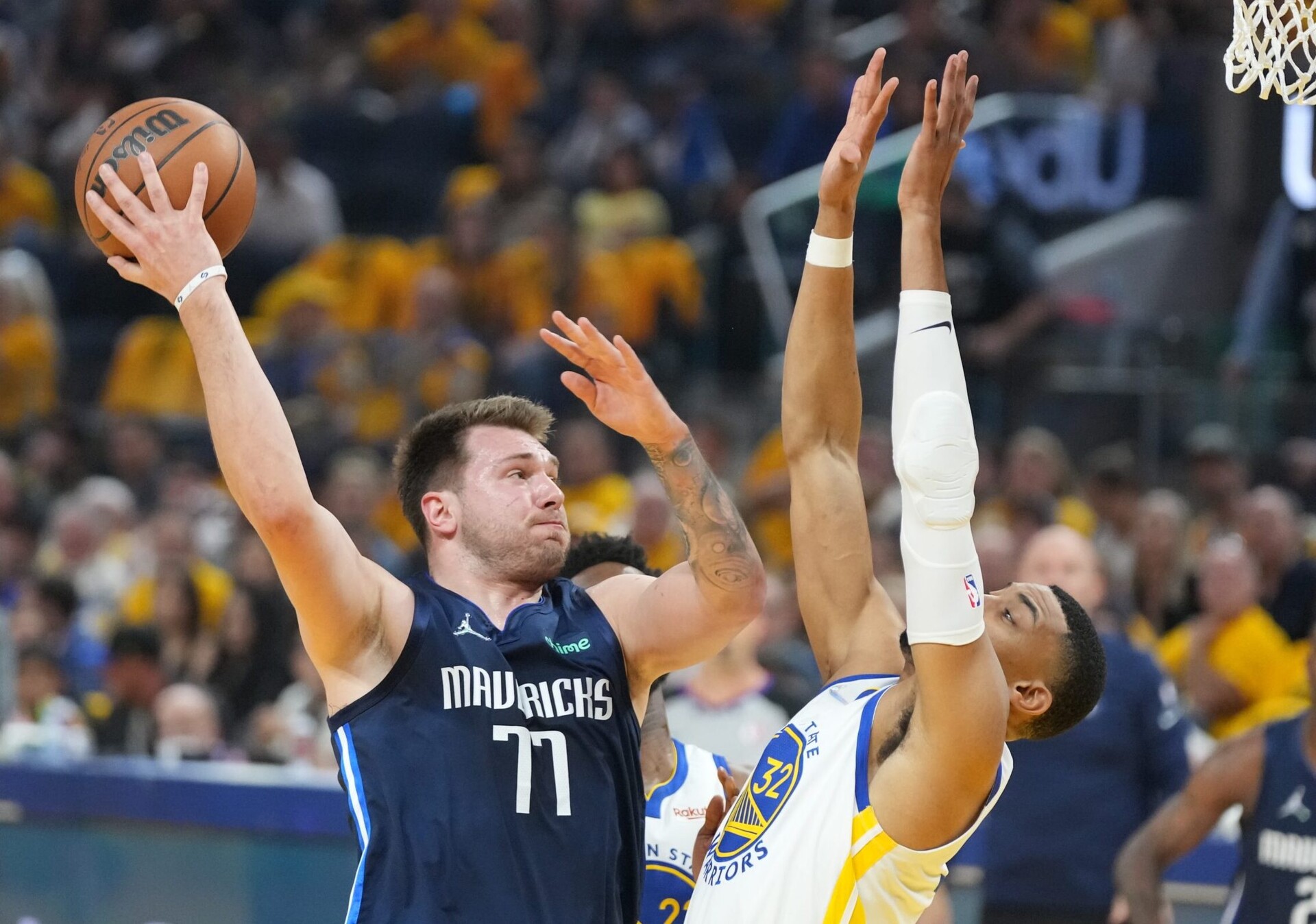 Dallas Mavericks guard Luka Doncic, left, throws a no-look pass behind his back with his right hand while being guarded by Golden State Warriors forward Otto Porter Jr., right with hands in the air, on Friday, May 20, 2022, in San Francisco.