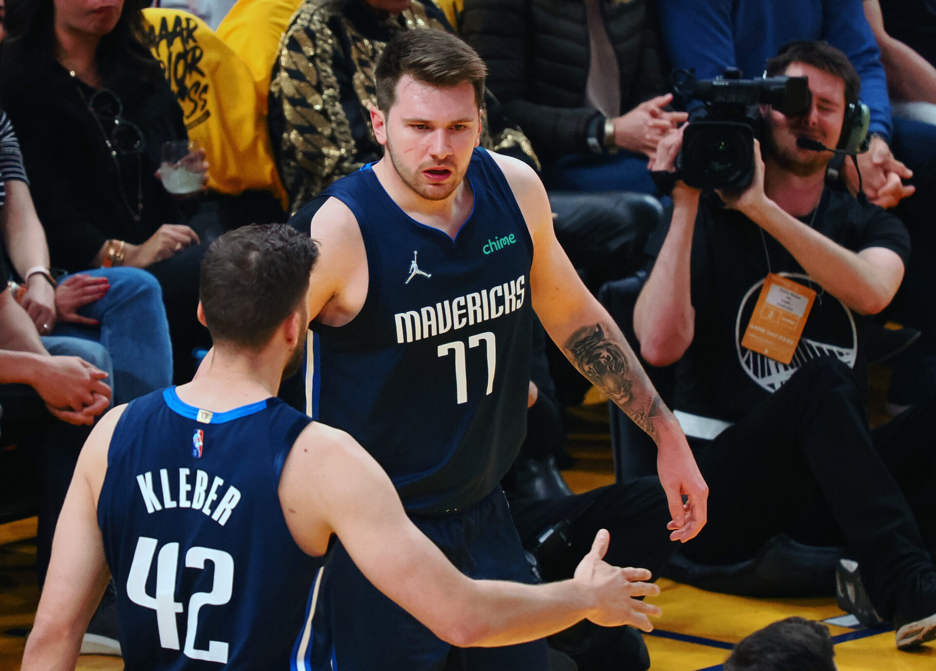Dallas Mavericks guard Luka Doncic, center, goes to slap hands with forward Maxi Kleber, left with back to camera, on Friday, May 20, 2022, in San Francisco.