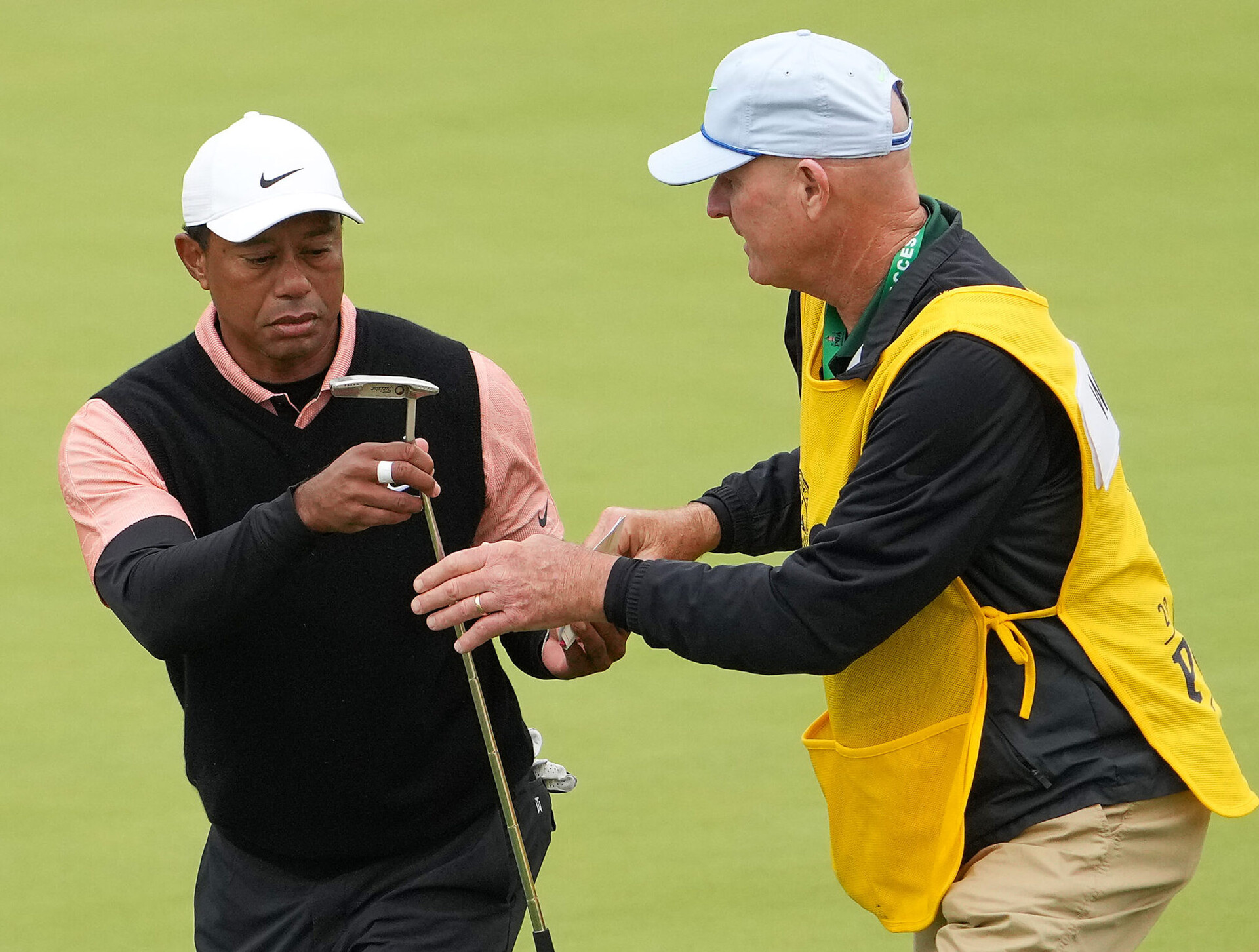 Tiger Woods, right, hands off his putter and grabs his scorecard from caddie Joe LaCava, right, after finishing the third round of the PGA Championship golf tournament at Southern Hills Country Club on May 21, 2022.
