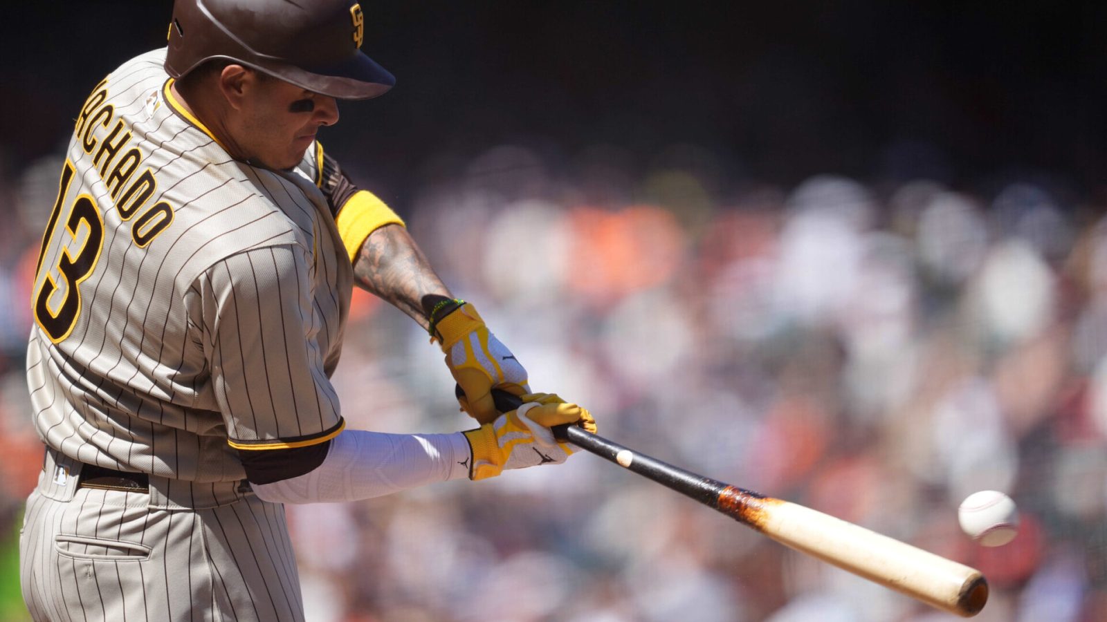 San Diego Padres third baseman Manny Machado swings his bat and is about to connect with a baseball that ends up as a double during a game against the San Francisco Giants