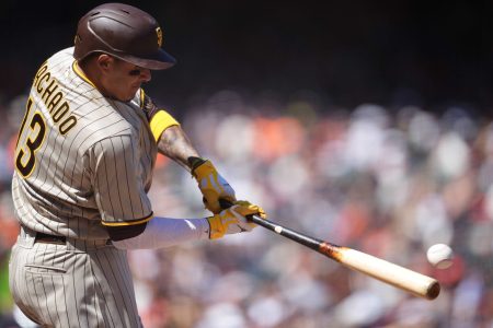San Diego Padres third baseman Manny Machado swings his bat and is about to connect with a baseball that ends up as a double during a game against the San Francisco Giants