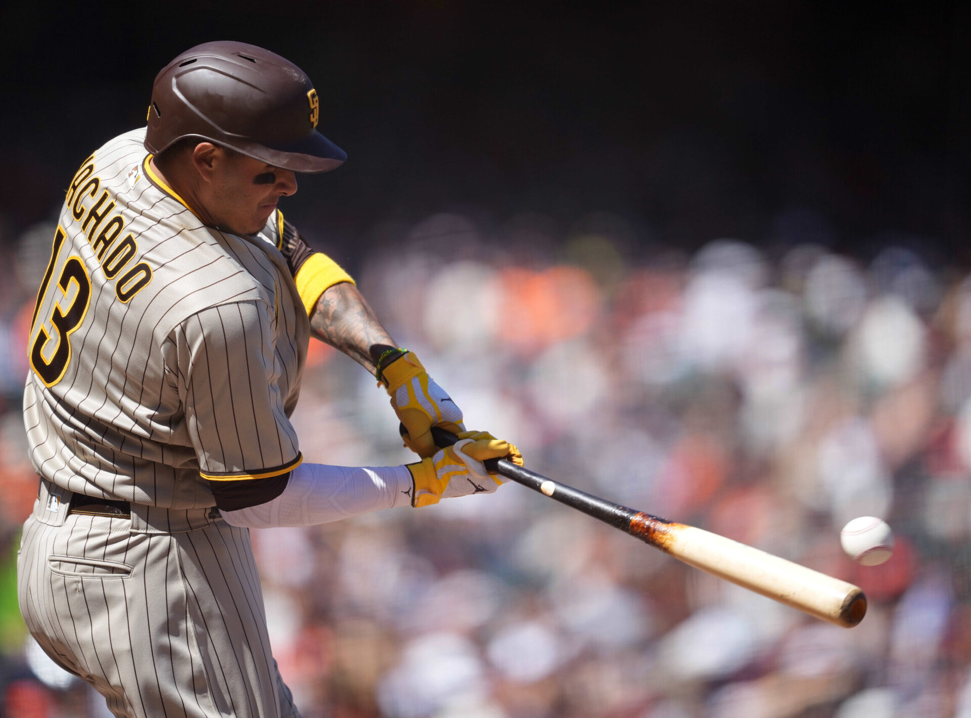 San Diego Padres third baseman Manny Machado swings his bat and is about to connect with a baseball that ends up as a double during a game against the San Francisco Giants