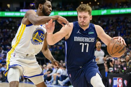 Dallas Mavericks guard Luka Doncic (right) dribbles the basketball with his left hand as he tries to get around Golden State Warriors defender Andrew Wiggins (left) during Game 3 of the NBA Western Conference Finals