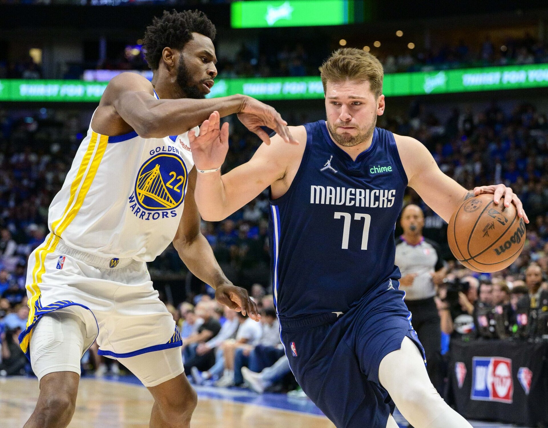 Dallas Mavericks guard Luka Doncic (right) dribbles the basketball with his left hand as he tries to get around Golden State Warriors defender Andrew Wiggins (left) during Game 3 of the NBA Western Conference Finals