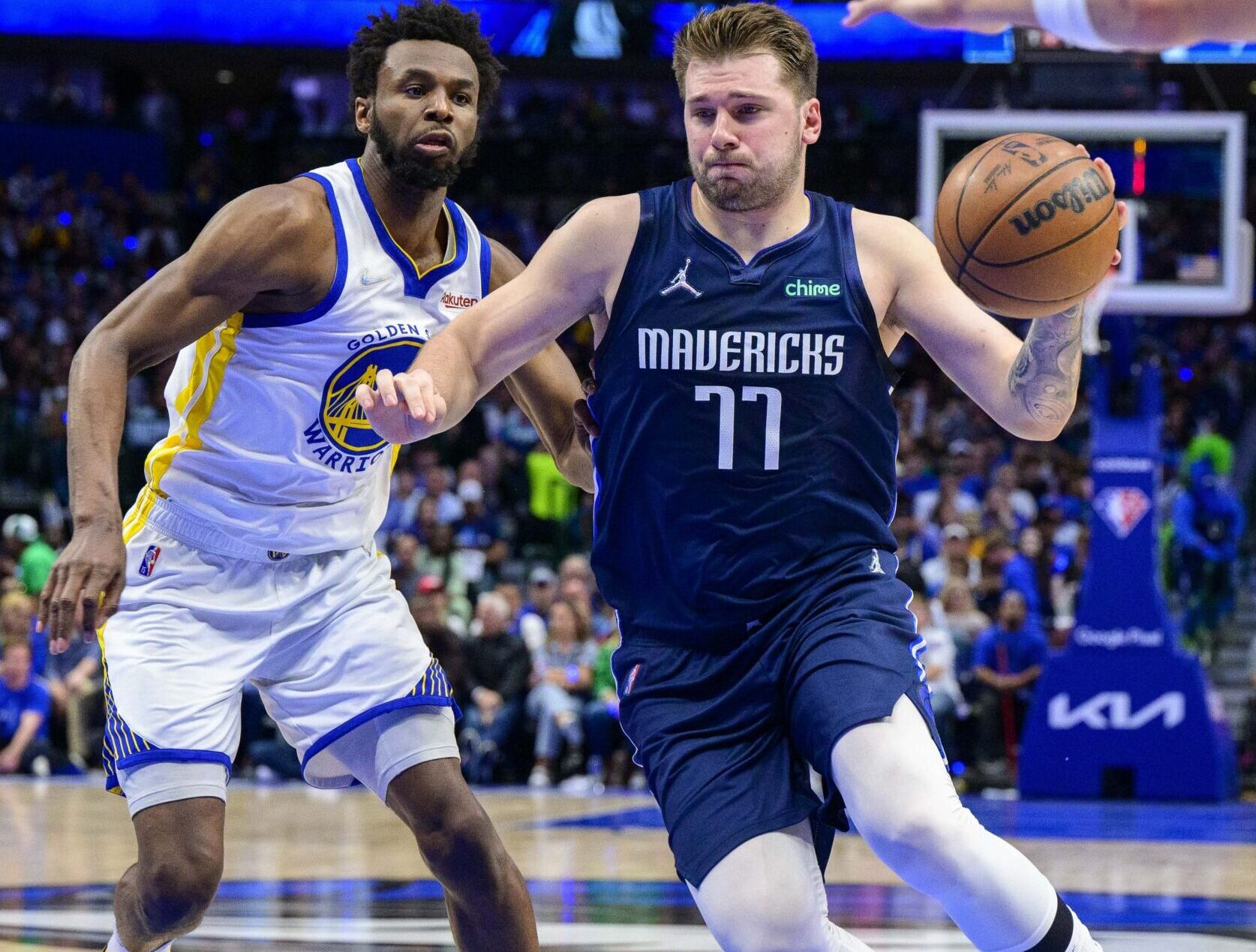 Dallas Mavericks guard Luka Doncic, right, drives to the basket with the ball in his left hand against Golden State Warriors forward Andrew Wiggins, left, on Sunday, May 22, 2022, in Dallas.