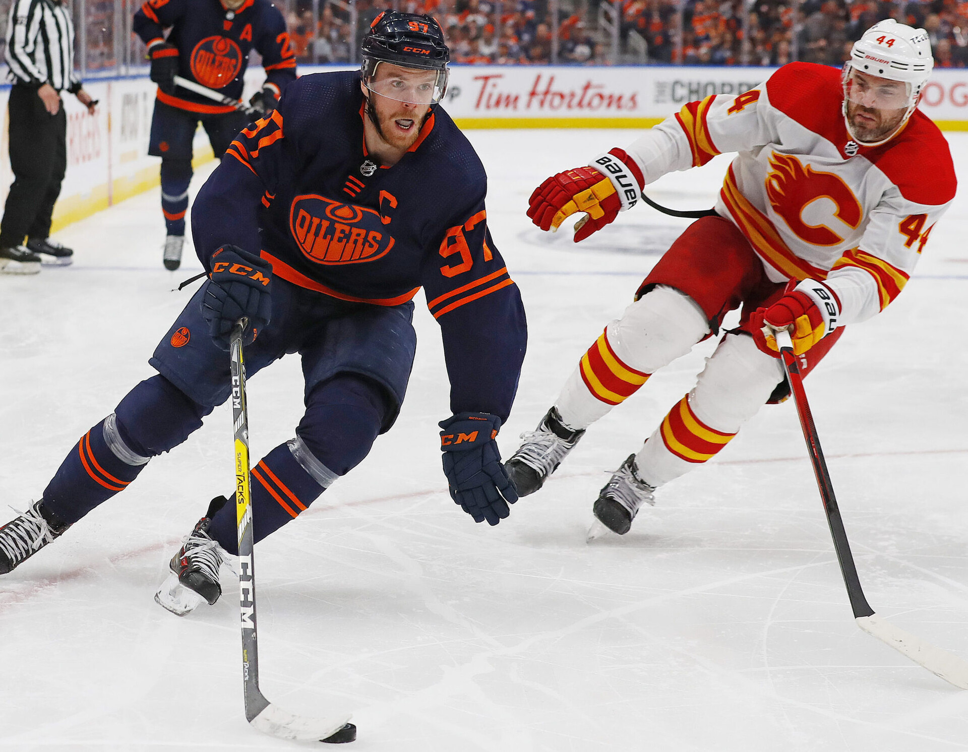 Edmonton Oilers forward Connor McDavid (left) carries the puck around Calgary Flames defensemen Erik Gudbranson (right) during Game 3 of the second round of the 2022 Stanley Cup Playoffs
