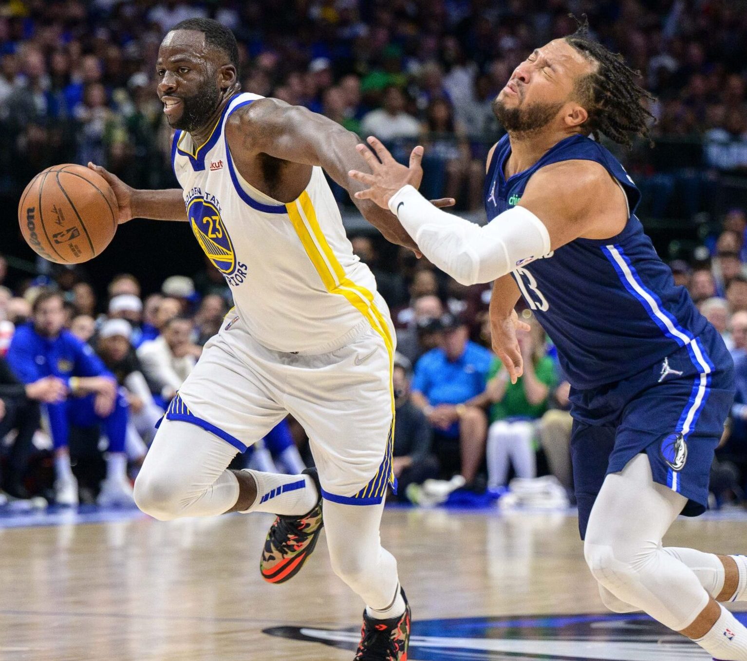 Golden State Warriors forward Draymond Green, left, drives past grimacing Dallas Mavericks guard Jalen Brunson, right, on Sunday, May 22, 2022, in Dallas.