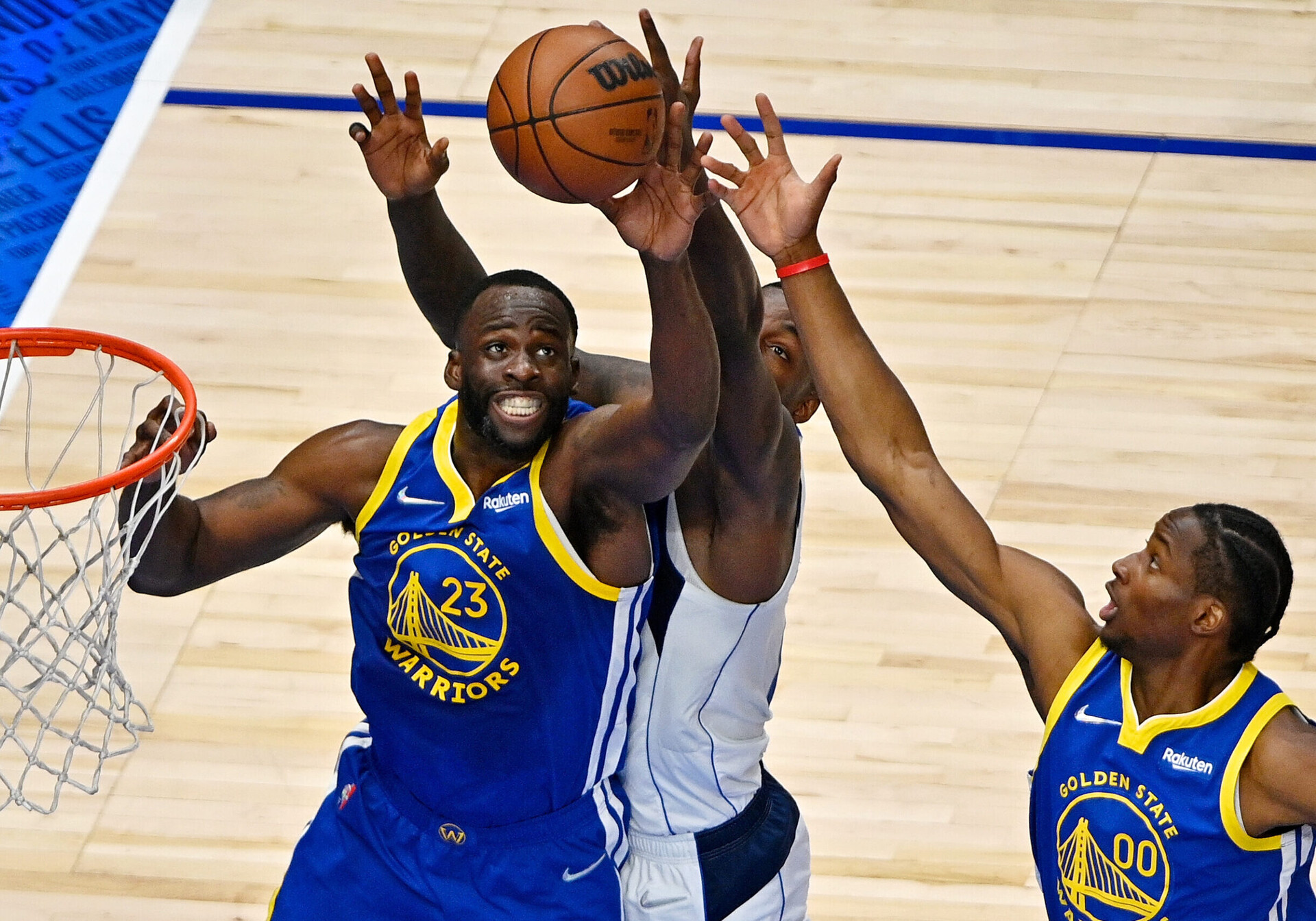 Golden State Warriors forward Draymond Green, center, leaps for a rebound in front of Dallas Mavericks forward Dorian Finney-Smith, back, and Warriors forward Jonathan Kuminga, right, on Tuesday, May 24, 2022, in Dallas.