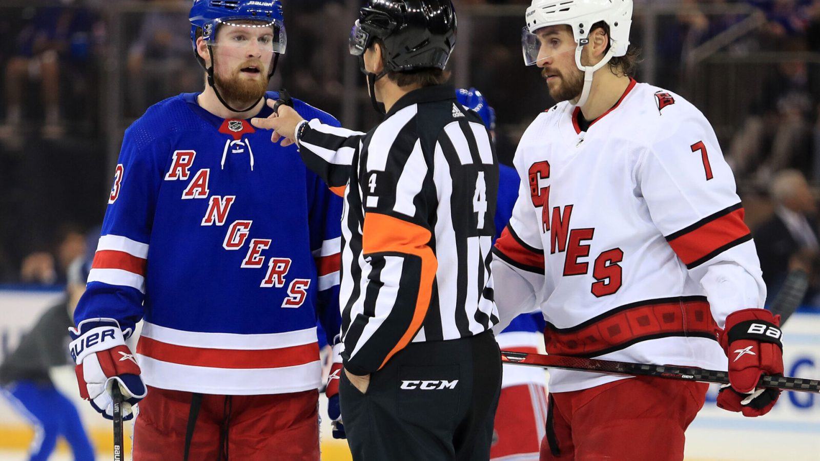 NHL referee Wes McCauley gestures to New York Rangers left wing Alexis Lafreniere (left) about his goalie interference call while Carolina Hurricanes defenseman Brendan Smith (right) listens in during Game 4 of the second round of the 2022 Stanley Cup Playoffs