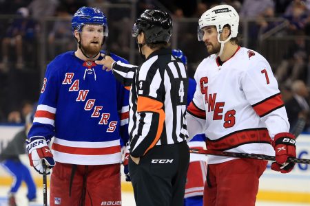 NHL referee Wes McCauley gestures to New York Rangers left wing Alexis Lafreniere (left) about his goalie interference call while Carolina Hurricanes defenseman Brendan Smith (right) listens in during Game 4 of the second round of the 2022 Stanley Cup Playoffs