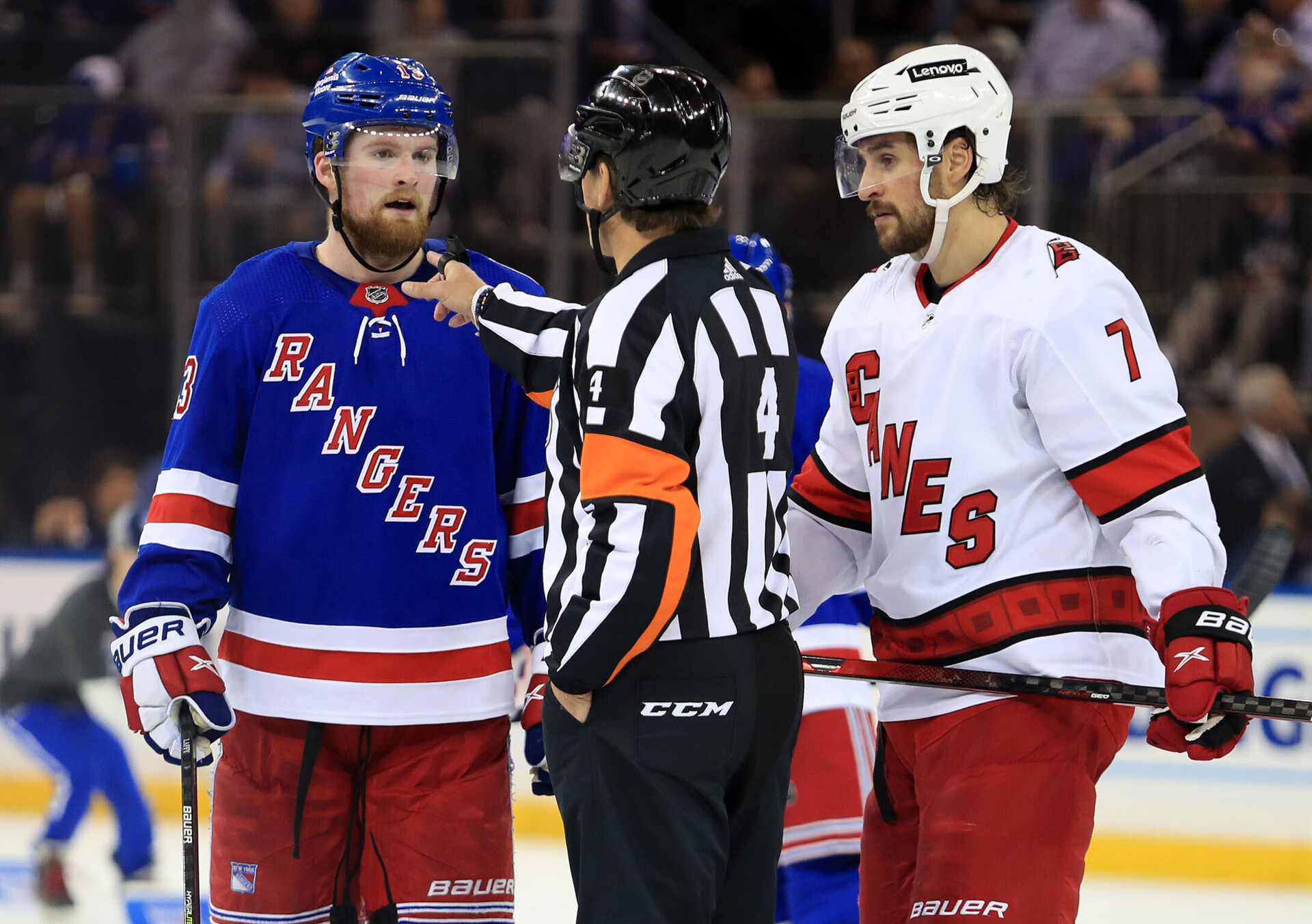 NHL referee Wes McCauley gestures to New York Rangers left wing Alexis Lafreniere (left) about his goalie interference call while Carolina Hurricanes defenseman Brendan Smith (right) listens in during Game 4 of the second round of the 2022 Stanley Cup Playoffs