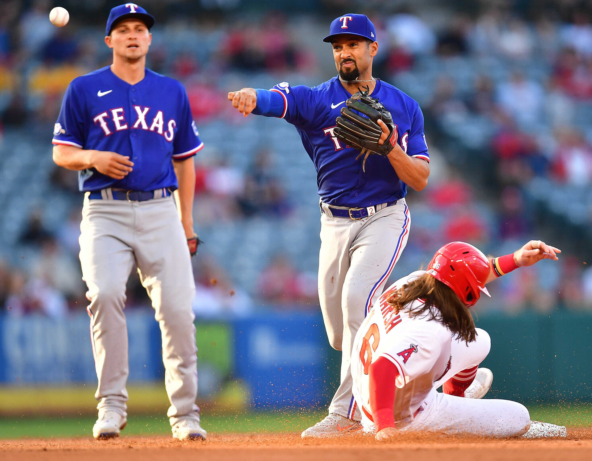Los Angeles Angels left fielder Brandon Marsh slides into second base after being forced out as Texas Rangers second baseman Marcus Semien throws to first to complete a double play. Also pictured is Rangers shortstop Corey Seager.