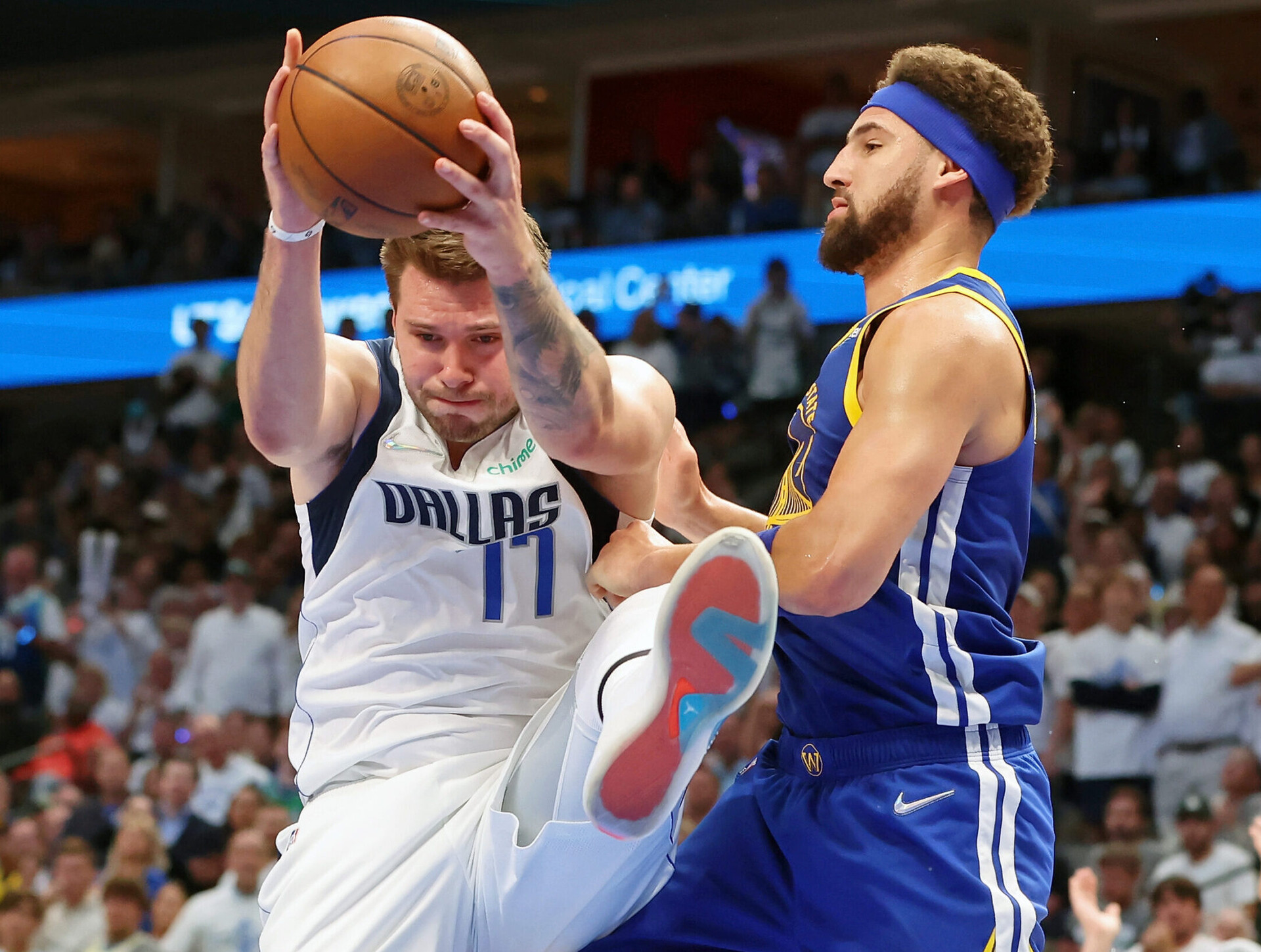 Dallas Mavericks guard Luka Doncic, left, grabs the ball with both hands while kicking his left leg in the air in front of Warriors guard Klay Thompson, right, on Tuesday, May 24, 2022, in Dallas.