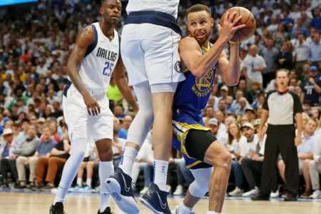 Golden State Warriors guard Stephen Curry, right, looks for an opening around leaping Dallas Mavericks forward Maxi Kleber, top of body out of frame, while Mavericks forward Reggie Bullock, left, watches on Tuesday, May 24, 2022, in Dallas.
