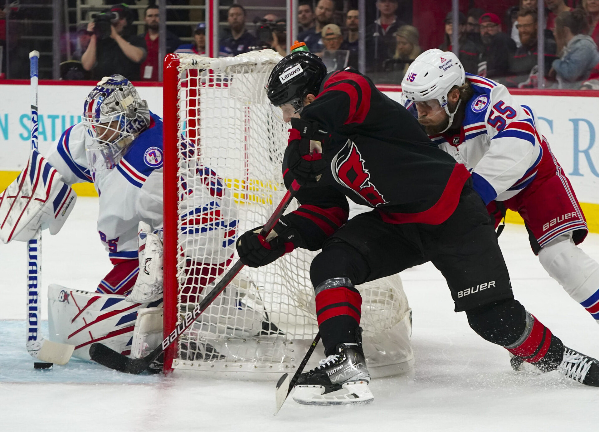 Carolina Hurricanes right wing Jesper Fast (center) shoots the puck on New York Rangers goaltender Igor Shesterkin (left) while Rangers defenseman Ryan Lindgren (right) applies pressure from behind during Game 5 of the 2022 Stanley Cup Playoffs