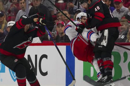 Carolina Hurricanes left wing Jordan Martinook (right) checks New York Rangers center Kevin Rooney (center) into the air during Game 5 of the second round of the 2022 Stanley Cup Playoffs