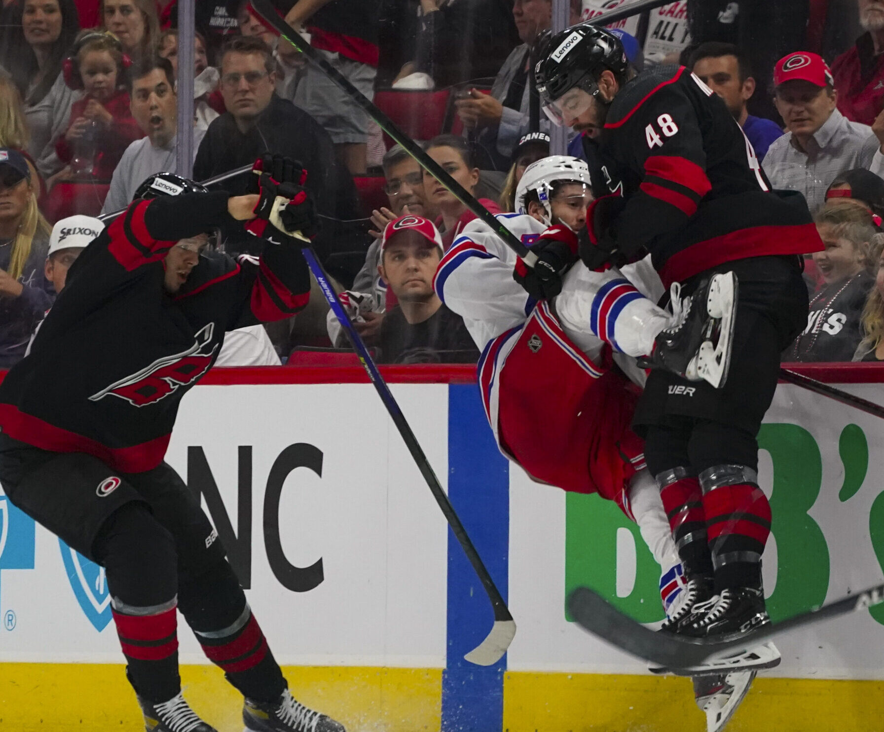Carolina Hurricanes left wing Jordan Martinook (right) checks New York Rangers center Kevin Rooney (center) into the air during Game 5 of the second round of the 2022 Stanley Cup Playoffs