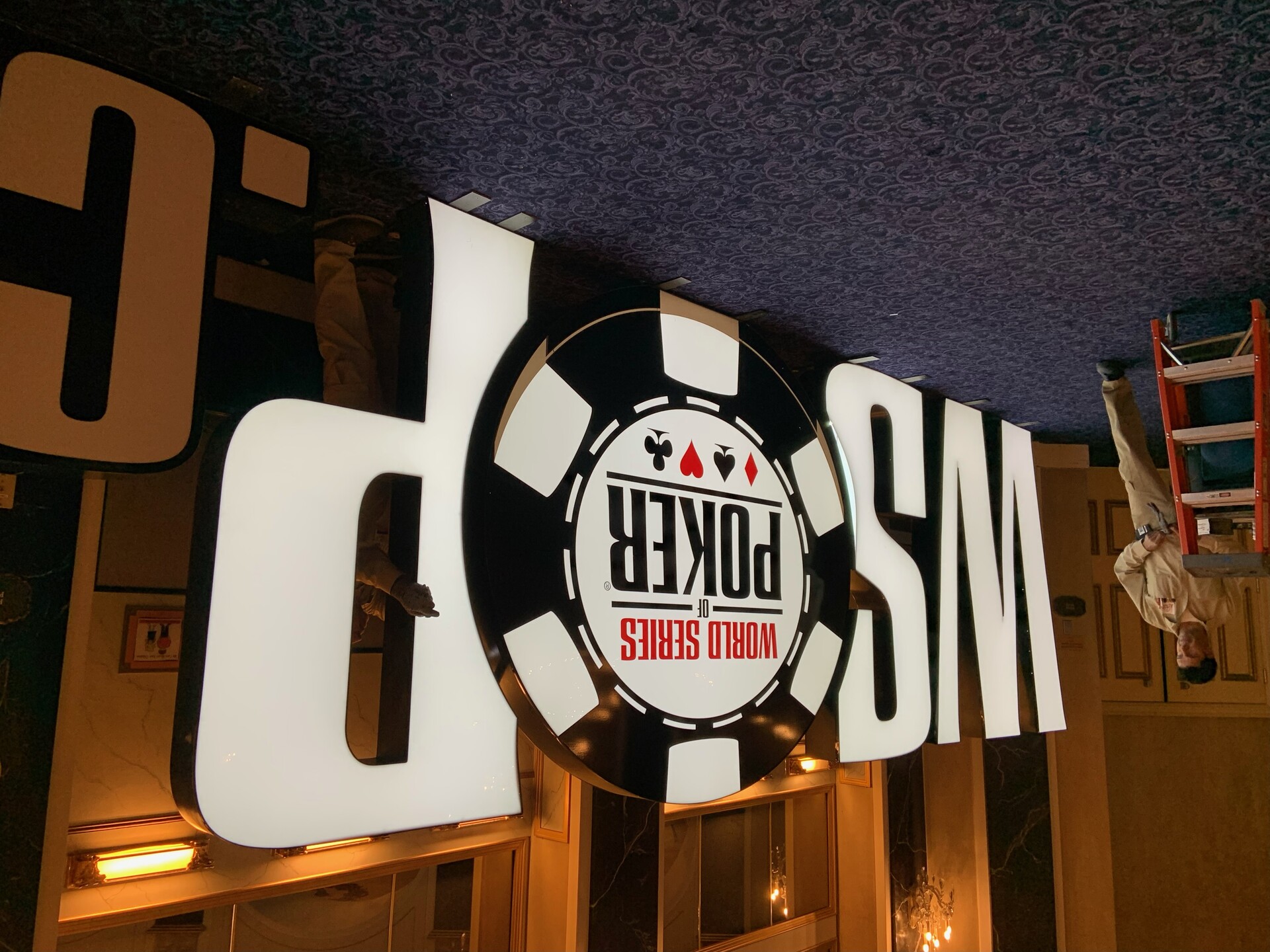 Workers install the World Series of Poker logo at the Paris Las Vegas convention center on Thursday, May 26, 2022.