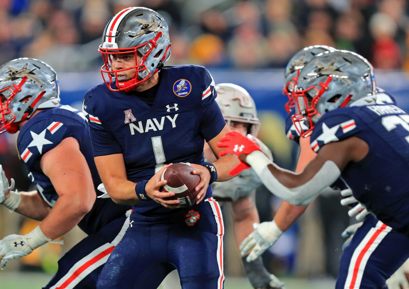 Navy Midshipmen quarterback Tai Lavatai, middle, hands off the ball against the Army Black Knights during the second half of the 122nd Army-Navy game on Dec. 11, 2021.