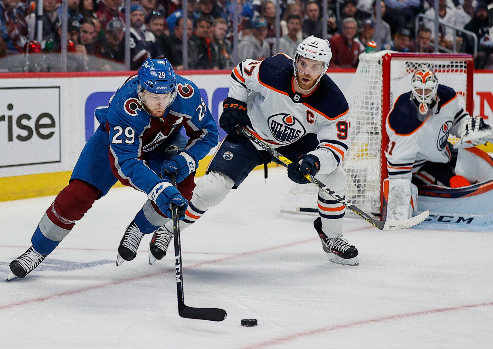 Colorado Avalanche center Nathan MacKinnon (left) controls the puck ahead of Edmonton Oilers center Connor McDavid (center) as Edmonton goalie Mike Smith defends his net in the third period in Game 2 of the Western Conference Final of the 2022 Stanley Cup Playoffs