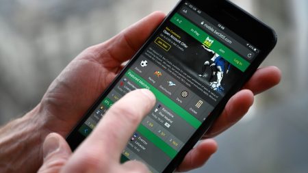 A man poses for a photograph with the online gambling website Bet365 displayed on a smartphone, in London on December 18, 2019. - Denise Coates, chief executive of British online betting giant Bet365, has retained her place as Britain's highest-paid boss, according to the group's annual report published on Wednesday. She was paid a basic salary of £277 million ($366 million, 328 million euros) in the group's financial year to March, the company's annual report showed.