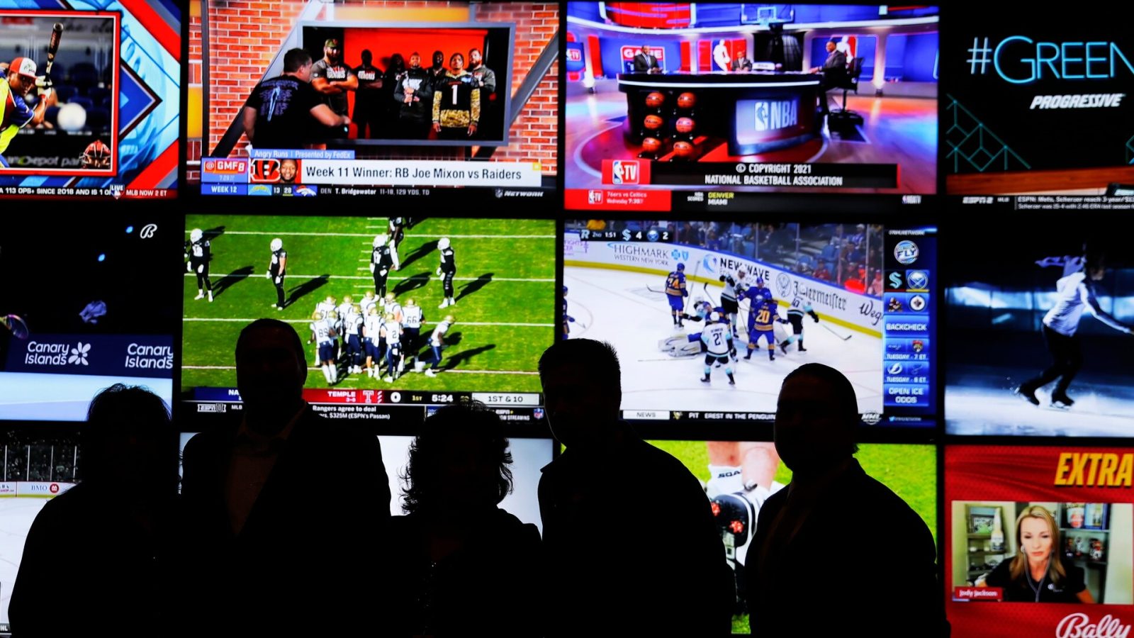 A group of people stand in front of a wall of televisions showing a variety of sports during the opening ceremony of the Oneida Casino's sports betting operation on Nov. 30, 2021, in Ashwaubenon, Wi