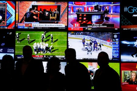 A group of people stand in front of a wall of televisions showing a variety of sports during the opening ceremony of the Oneida Casino's sports betting operation on Nov. 30, 2021, in Ashwaubenon, Wi