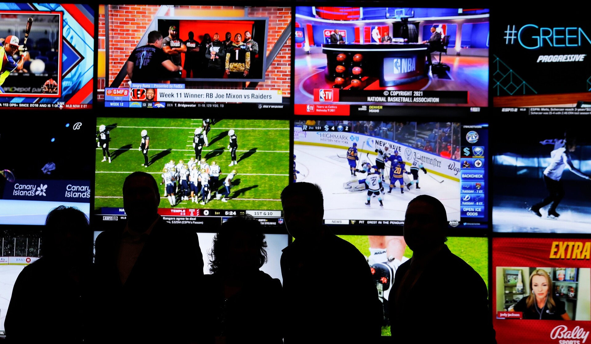 A group of people stand in front of a wall of televisions showing a variety of sports during the opening ceremony of the Oneida Casino's sports betting operation on Nov. 30, 2021, in Ashwaubenon, Wi
