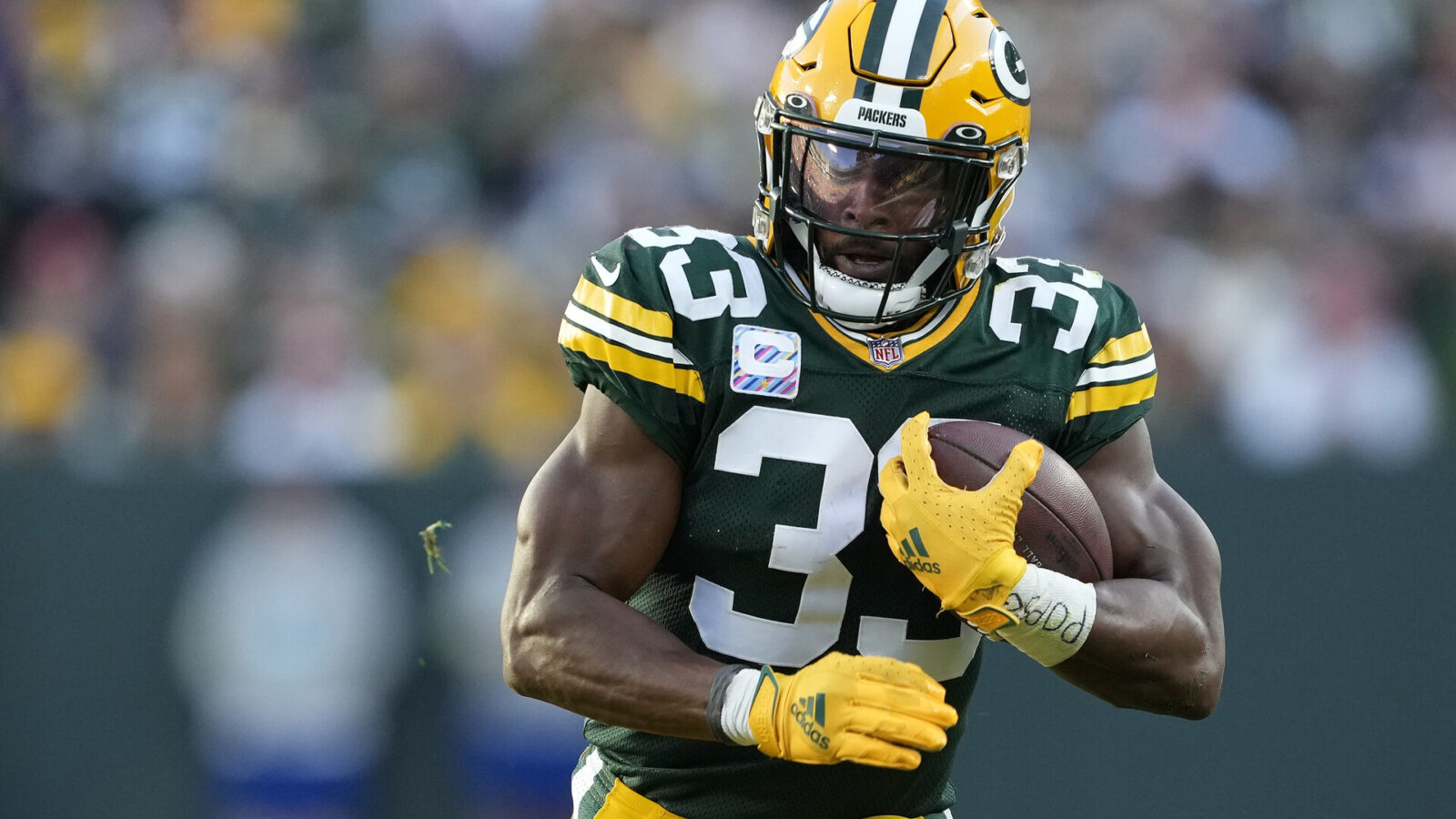 Aaron Jones #33 of the Green Bay Packers runs with the ball in the third quarter against the New England Patriots at Lambeau Field on October 02, 2022 in Green Bay, Wisconsin.