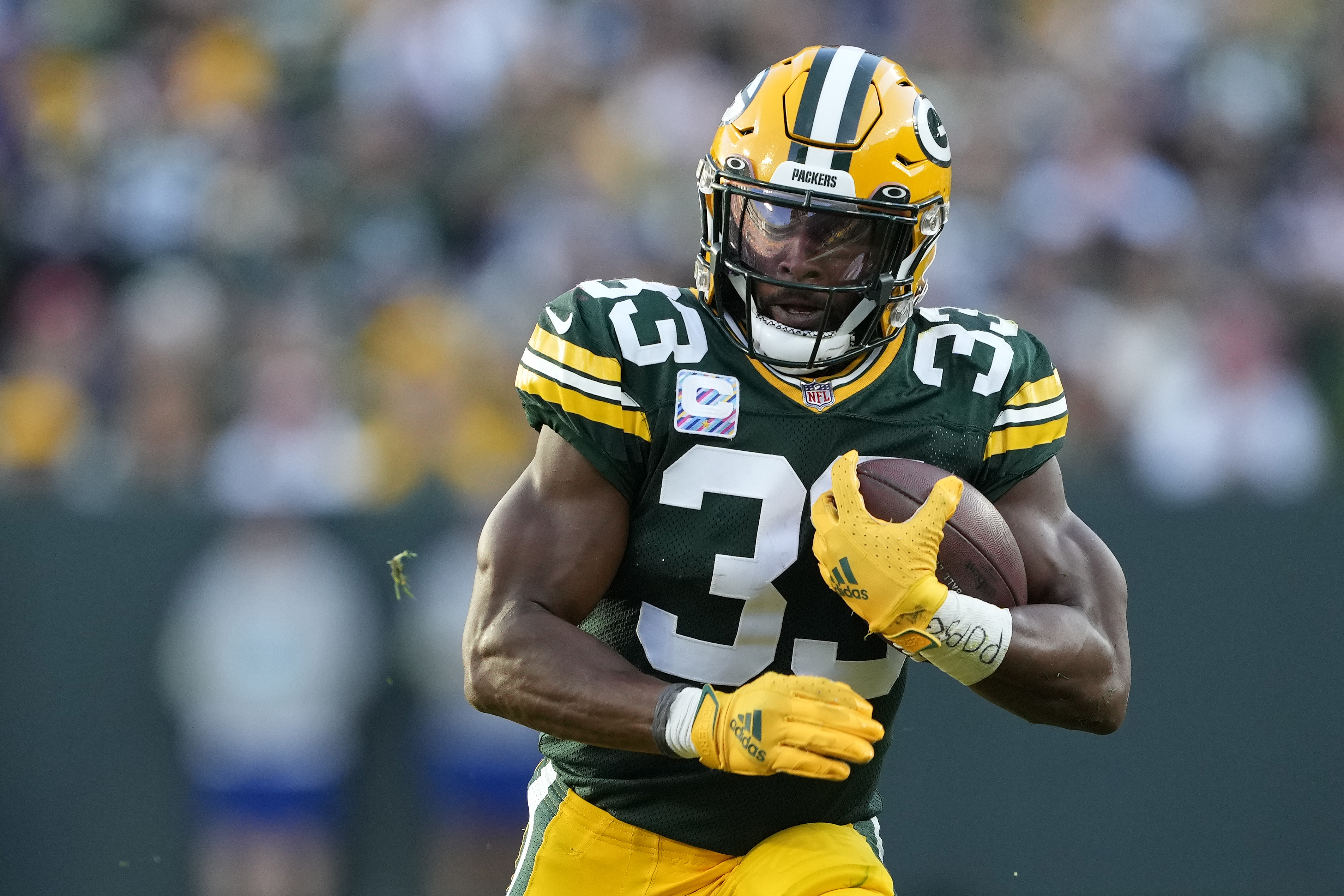 Aaron Jones #33 of the Green Bay Packers runs with the ball in the third quarter against the New England Patriots at Lambeau Field on October 02, 2022 in Green Bay, Wisconsin.