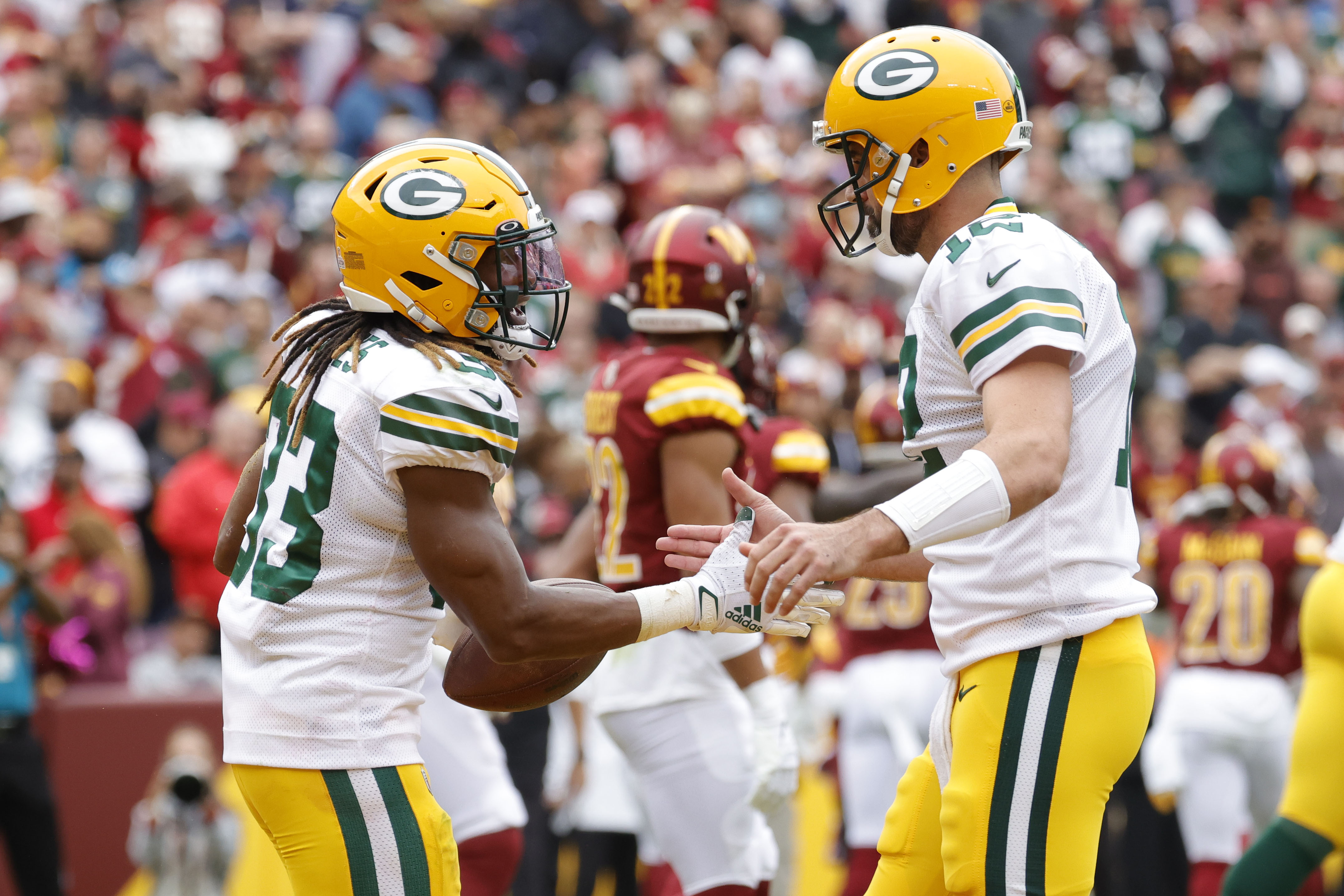 Oct 23, 2022; Landover, Maryland, USA; Green Bay Packers running back Aaron Jones (33) /celebrates with Packers quarterback Aaron Rodgers (12) after scoring a touchdown against the Washington Commanders during the first quarter at FedExField.