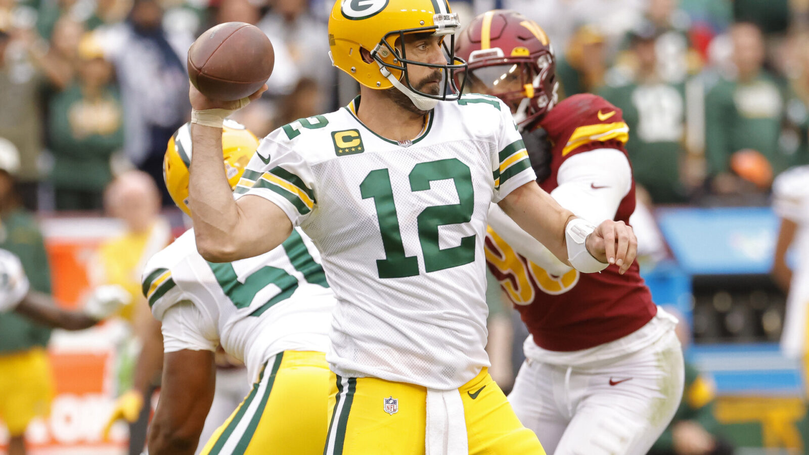 Oct 23, 2022; Landover, Maryland, USA; Green Bay Packers quarterback Aaron Rodgers (12) passes the ball as Washington Commanders defensive end Montez Sweat (90) chases during the fourth quarter at FedExField.