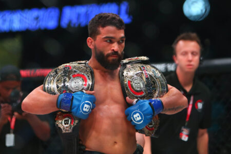 Patricio Freire (blue gloves) celebrates with his championship belts after defeating Michael Chandler (red gloves) during Bellator 221 at Allstate Arena.
