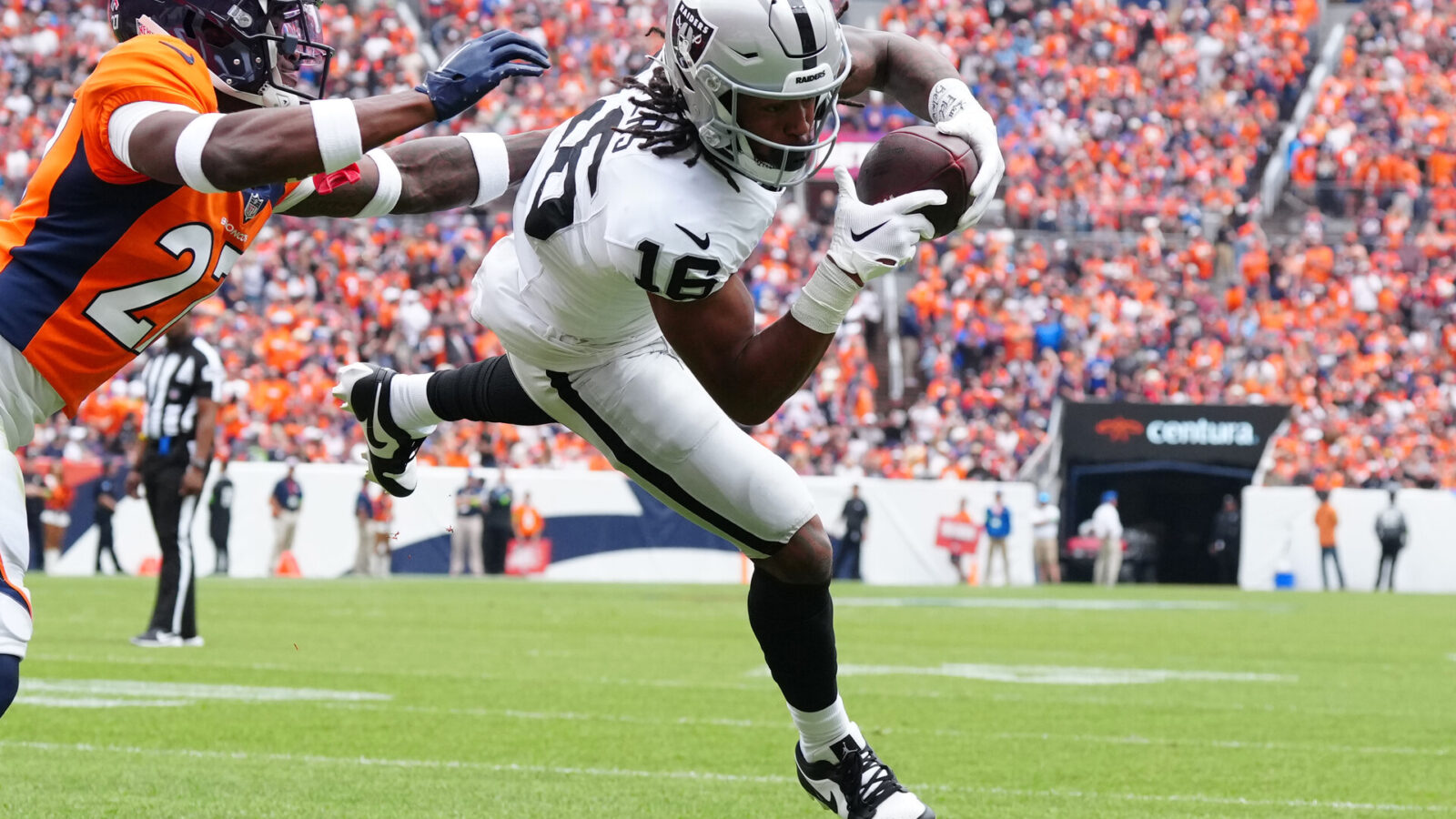 Las Vegas Raiders wide receiver Jakobi Meyers (16) catches a touchdown pass with Denver Broncos cornerback Damarri Mathis (27) defending in the first quarter at Empower Field at Mile High.