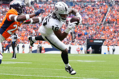 Las Vegas Raiders wide receiver Jakobi Meyers (16) catches a touchdown pass with Denver Broncos cornerback Damarri Mathis (27) defending in the first quarter at Empower Field at Mile High.