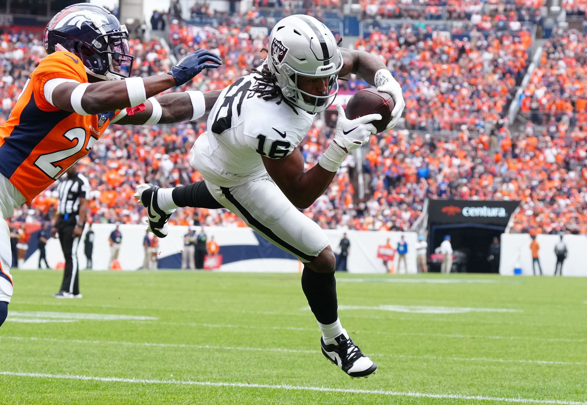 Las Vegas Raiders wide receiver Jakobi Meyers (16) catches a touchdown pass with Denver Broncos cornerback Damarri Mathis (27) defending in the first quarter at Empower Field at Mile High.