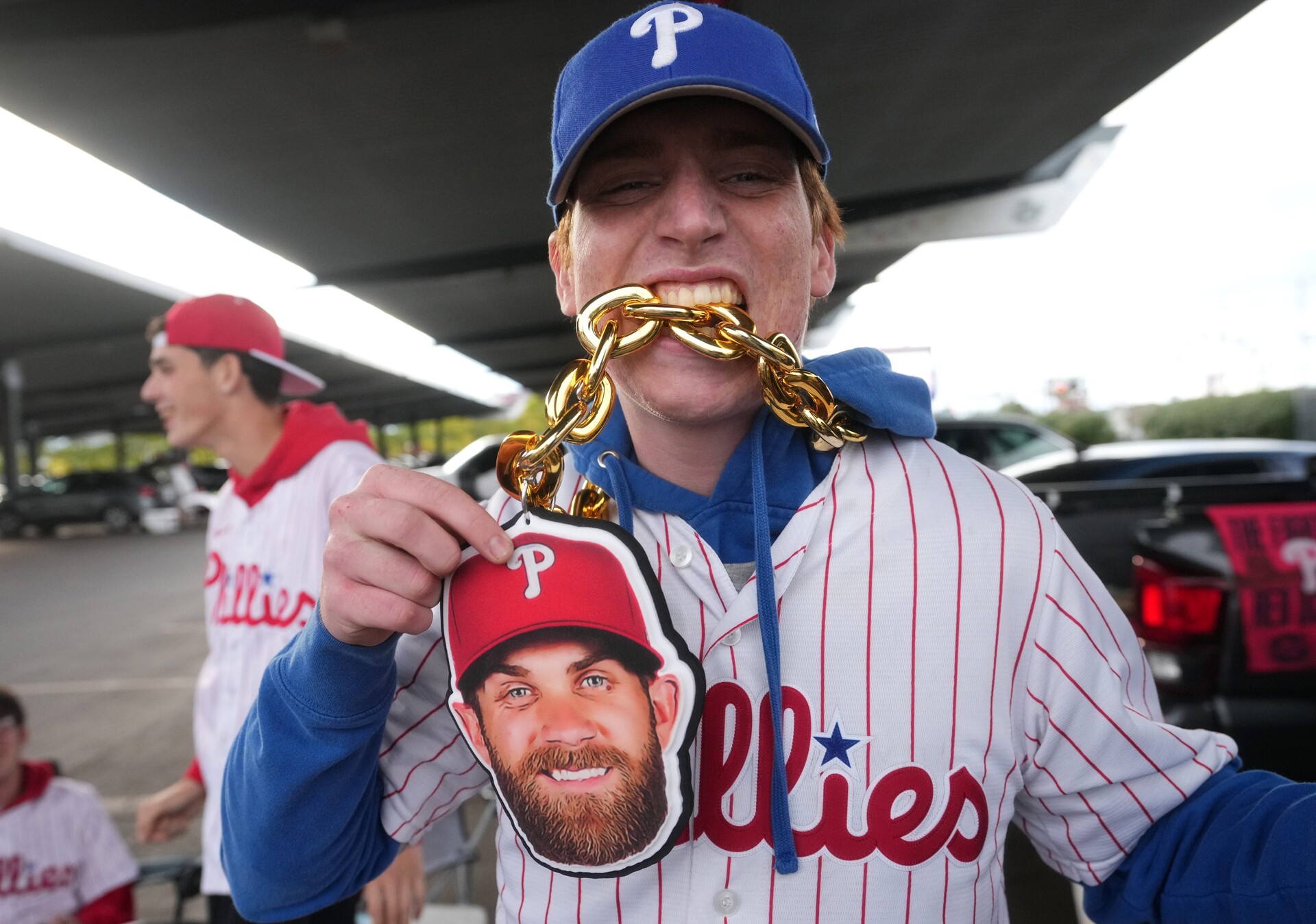 Sean McIvor takes a bite of his Bryce Harper chain at Citizens Bank Park before the gates open on their NLCS game against the Arizona Diamondbacks at Citizens Bank Park in Philadelphia on Oct. 16, 2023.