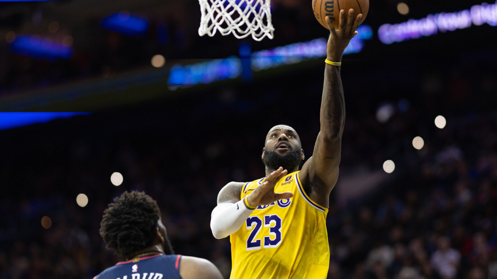 Nov 27, 2023; Philadelphia, Pennsylvania, USA; Los Angeles Lakers forward LeBron James (23) scores past Philadelphia 76ers center Joel Embiid (21) during the second quarter at Wells Fargo Center.