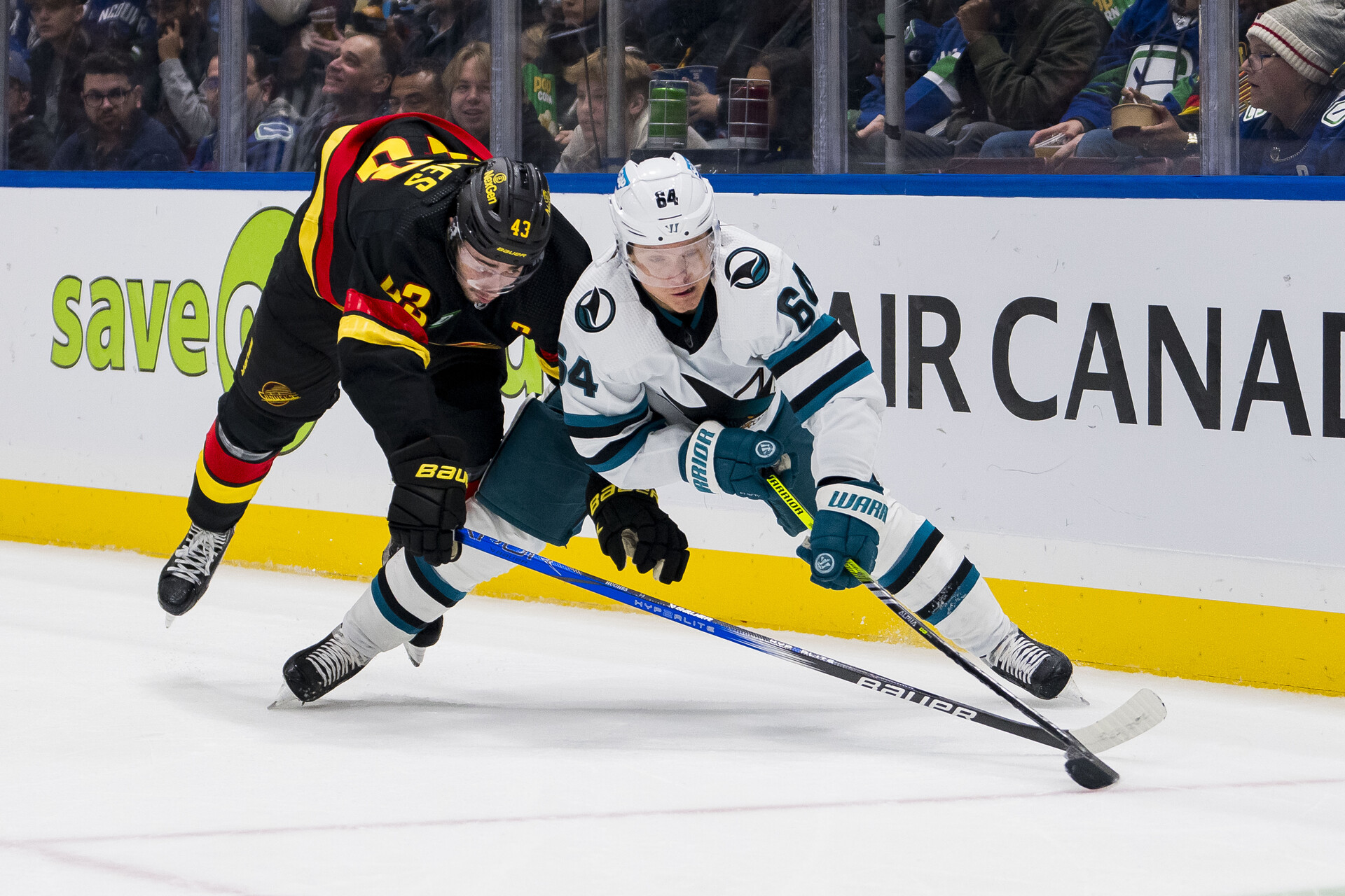 Nov 20, 2023; Vancouver, British Columbia, CAN; Vancouver Canucks defenseman Quinn Hughes (43) battles with San Jose Sharks forward Mikael Granlund (64) in the second period at Rogers Arena.