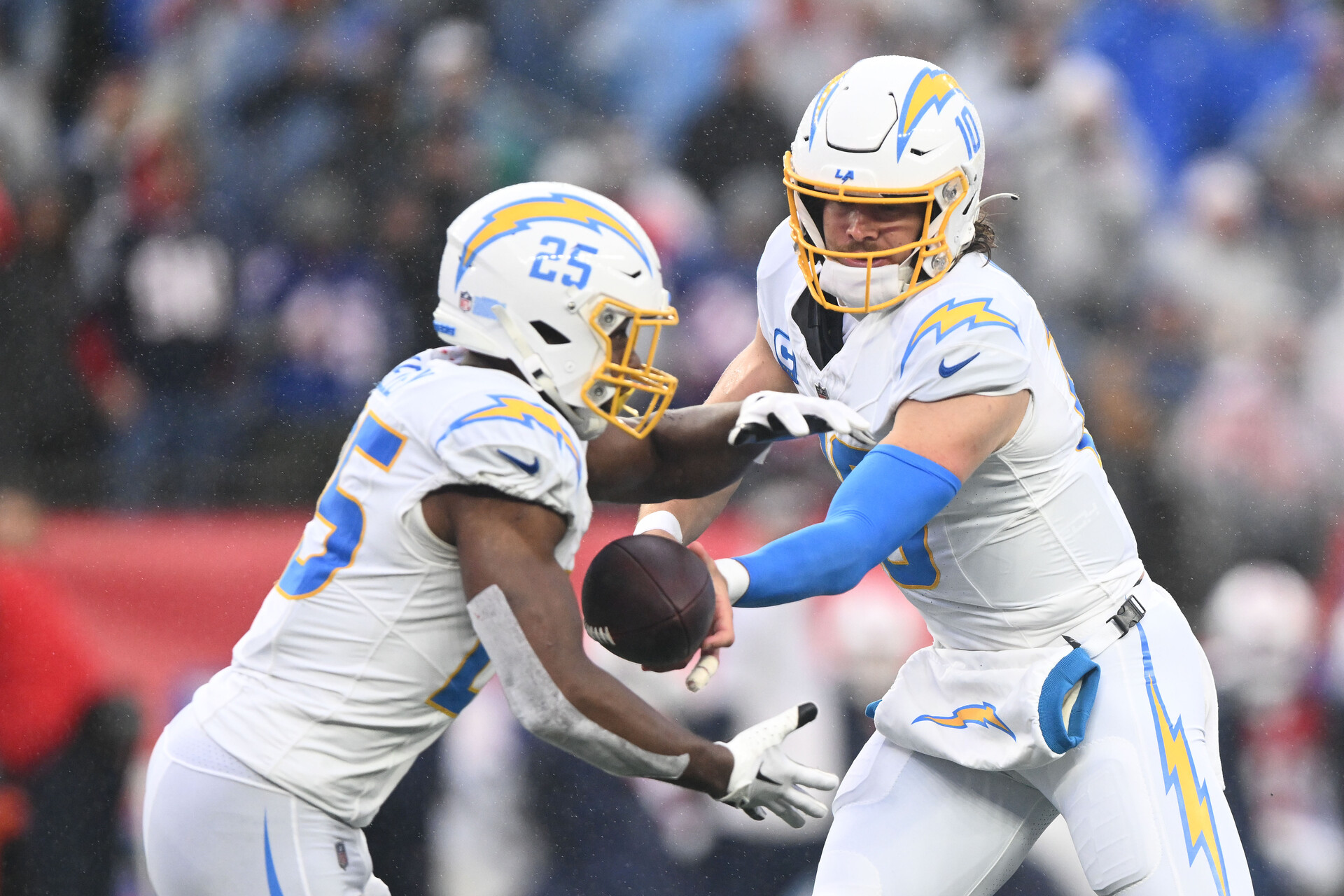 Dec 3, 2023; Foxborough, Massachusetts, USA; Los Angeles Chargers quarterback Justin Herbert (10) hands the ball off to running back Joshua Kelley (25) during the first half of a game against the New England Patriots at Gillette Stadium.