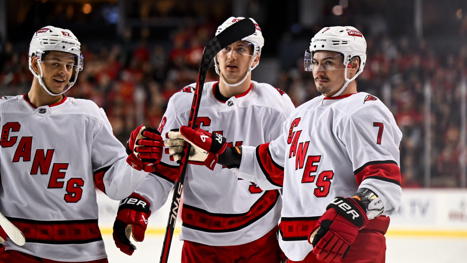 Dec 7, 2023; Calgary, Alberta, CAN; Carolina Hurricanes defenseman Dmitri Orlov (7) celebrates with center Jesperi Kotkaniemi (82) and center Martin Necas (88) after scoring a goal against the Calgary Flames during the first period of a game at Scotiabank Saddledome.