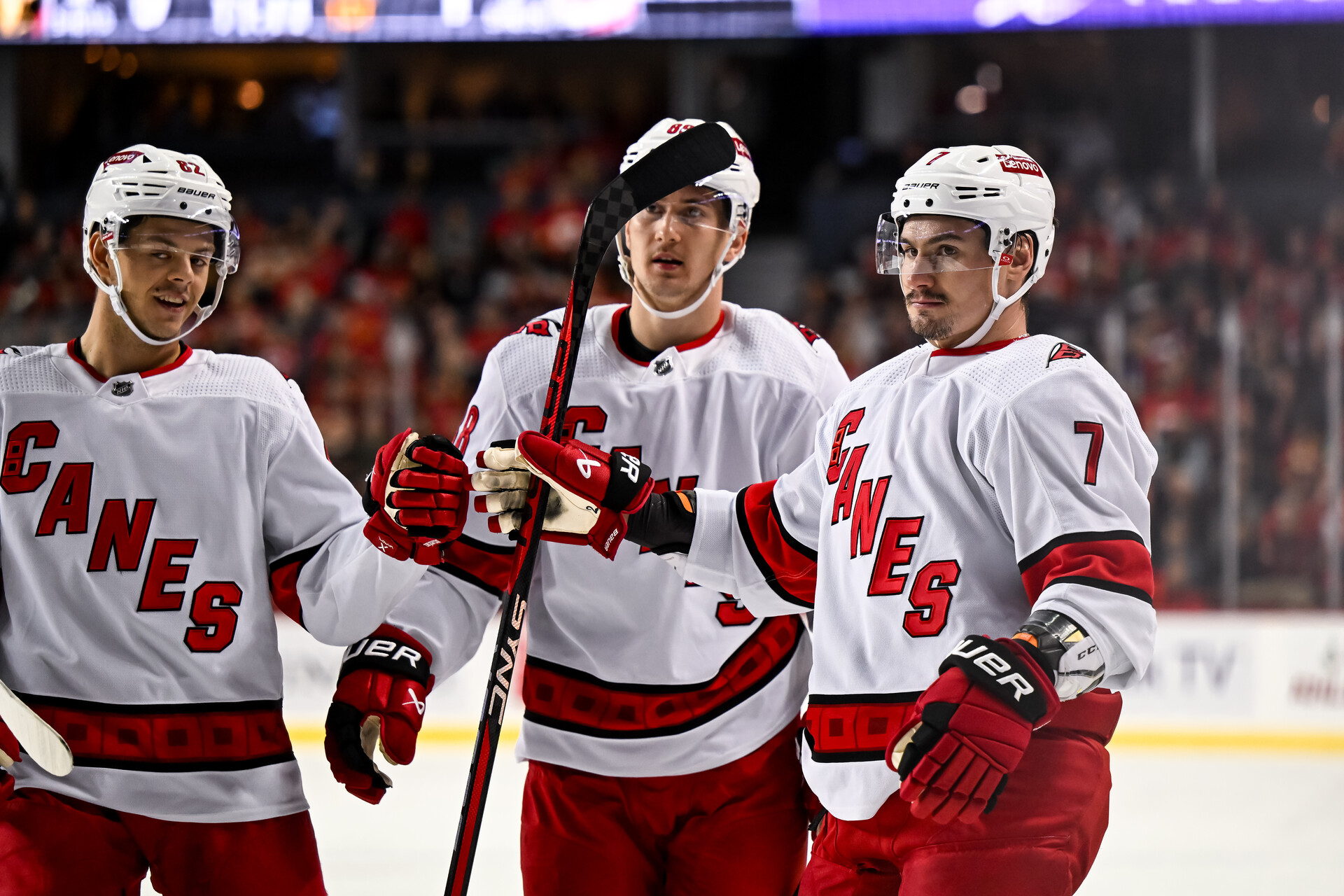 Dec 7, 2023; Calgary, Alberta, CAN; Carolina Hurricanes defenseman Dmitri Orlov (7) celebrates with center Jesperi Kotkaniemi (82) and center Martin Necas (88) after scoring a goal against the Calgary Flames during the first period of a game at Scotiabank Saddledome.