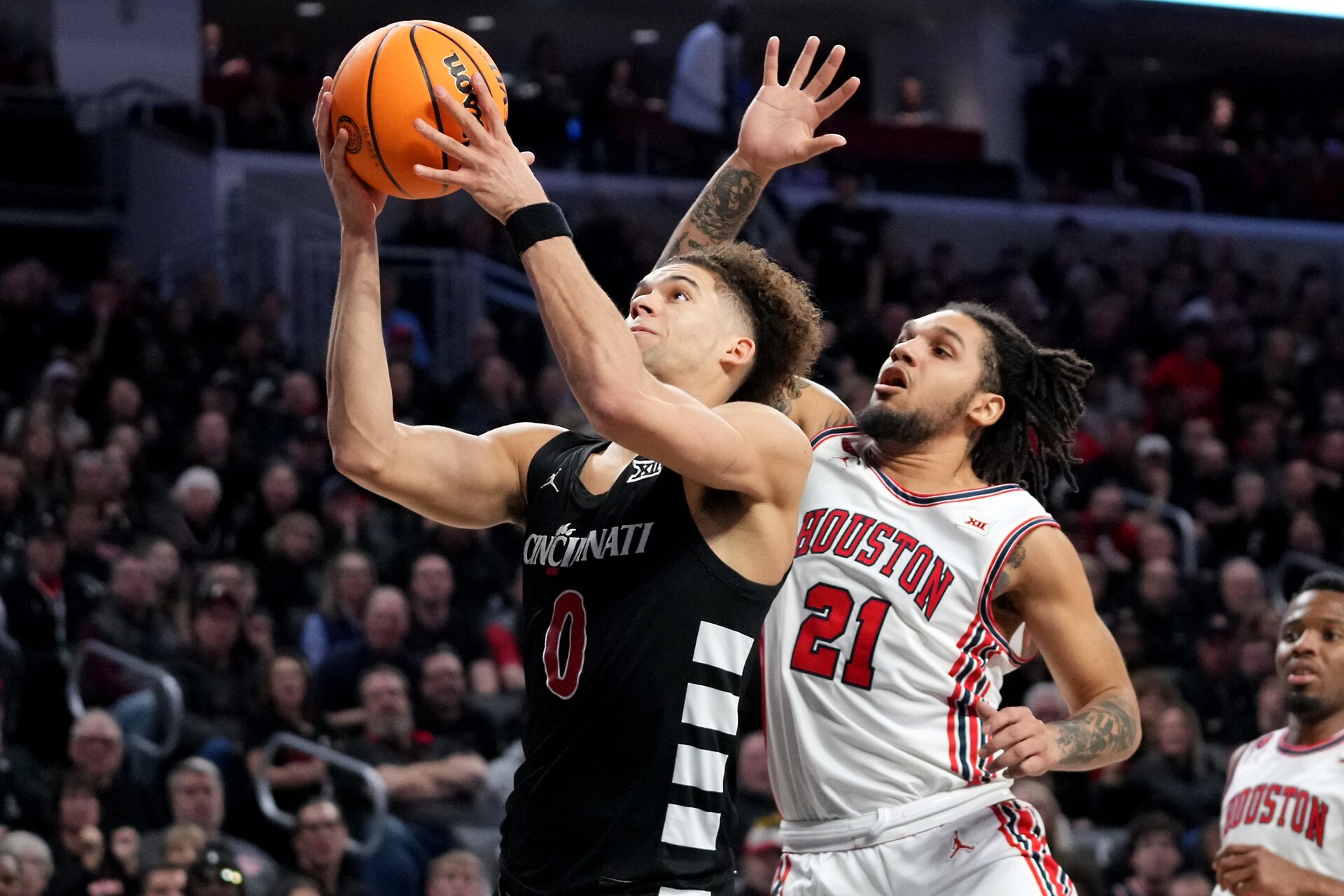 Cincinnati Bearcats guard Dan Skillings Jr. (0) rises to the basket as Houston Cougars guard Emanuel Sharp (21) defends in the second half of an NCAA college basketball game between the Houston Cougars and the Cincinnati Bearcats, Saturday, Feb. 10, 2024, at Fifth Third Arena in Cincinnati.