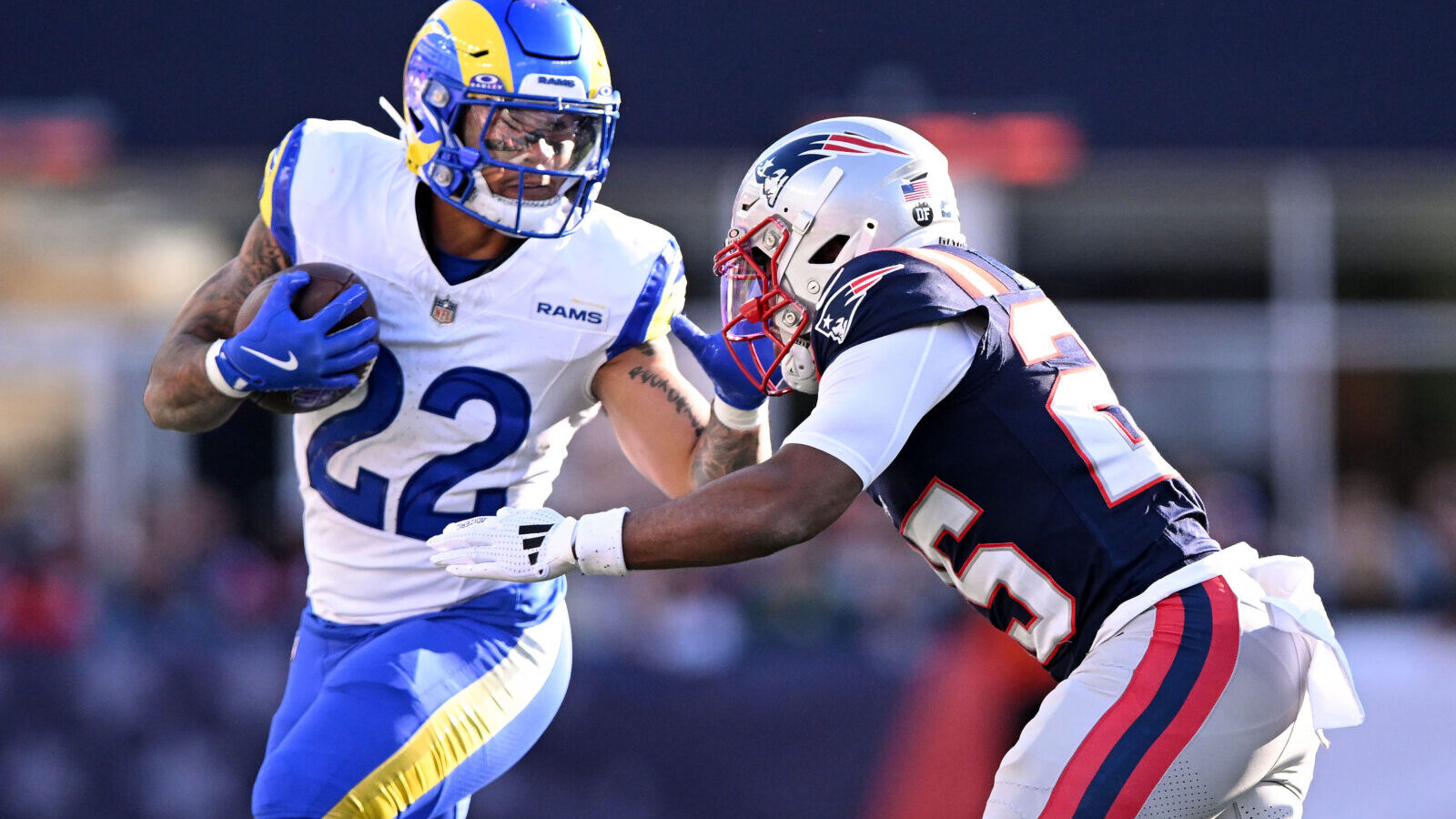 Nov 17, 2024; Foxborough, Massachusetts, USA; Los Angeles Rams running back Blake Corum (22) runs with the ball against New England Patriots cornerback Marcus Jones (25) during the first half at Gillette Stadium.
