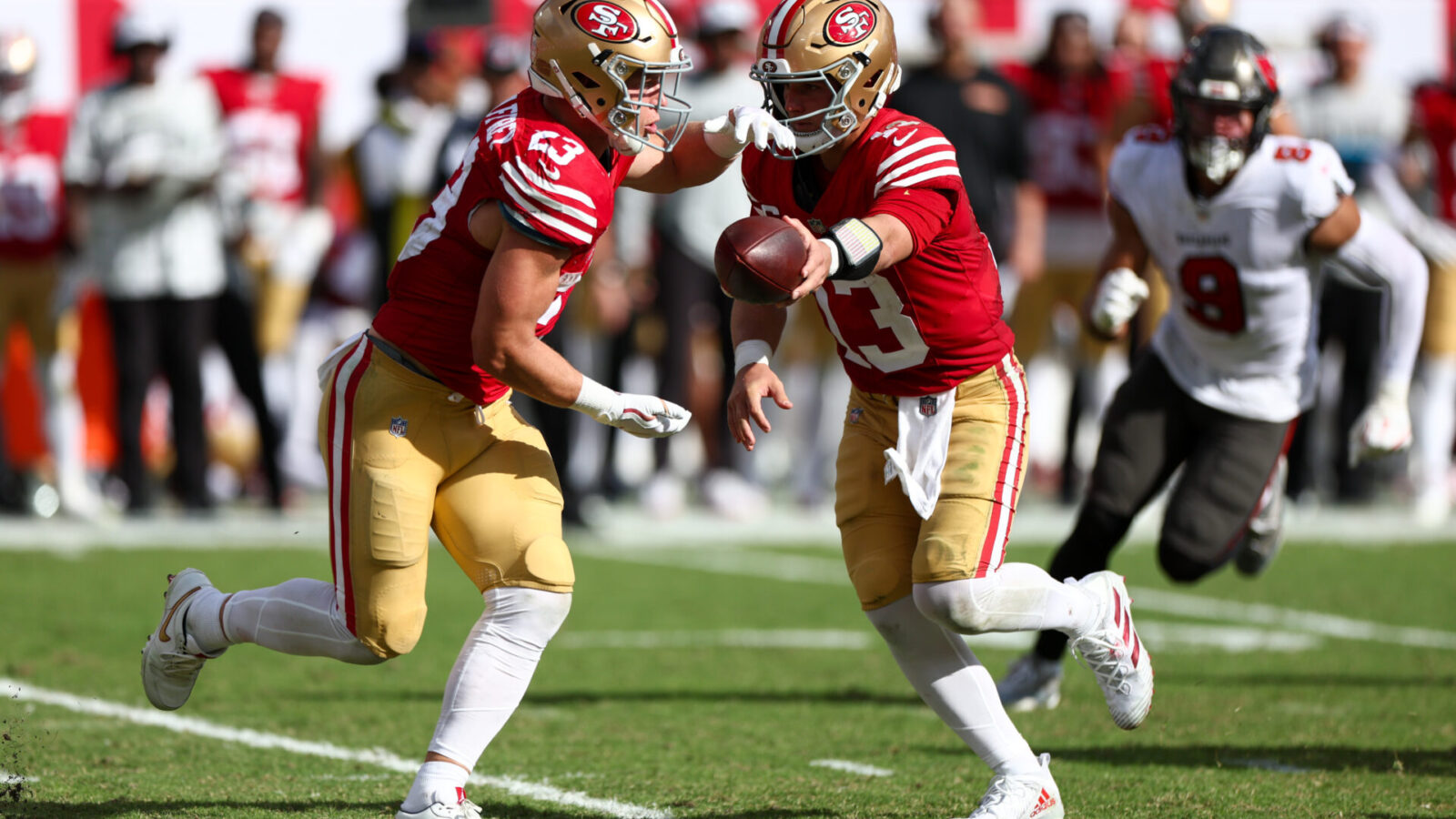 Nov 10, 2024; Tampa, Florida, USA; San Francisco 49ers quarterback Brock Purdy (13) hands off to running back Christian McCaffrey (23) against the Tampa Bay Buccaneers in the third quarter at Raymond James Stadium.