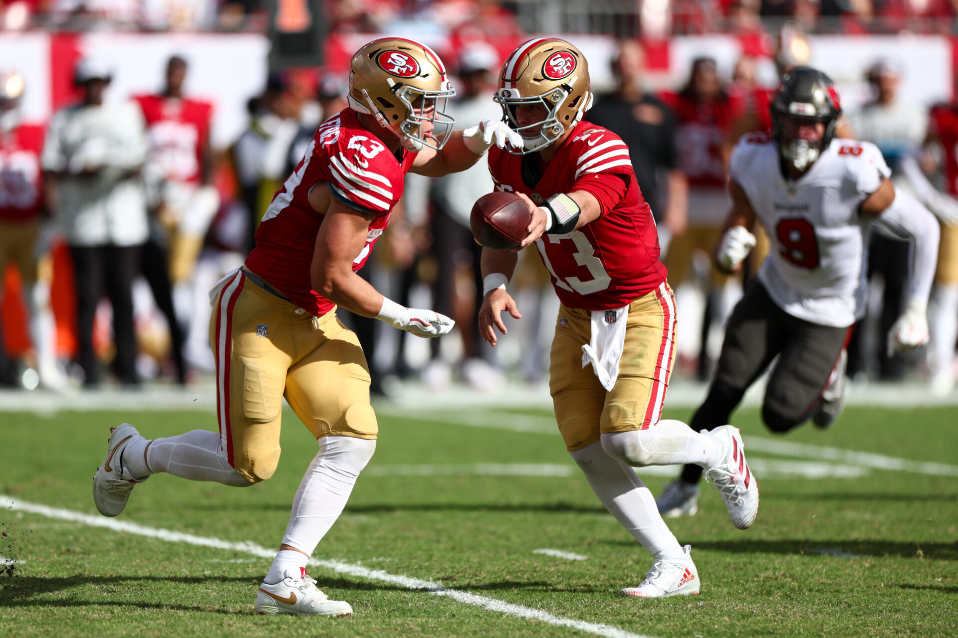 Nov 10, 2024; Tampa, Florida, USA; San Francisco 49ers quarterback Brock Purdy (13) hands off to running back Christian McCaffrey (23) against the Tampa Bay Buccaneers in the third quarter at Raymond James Stadium.