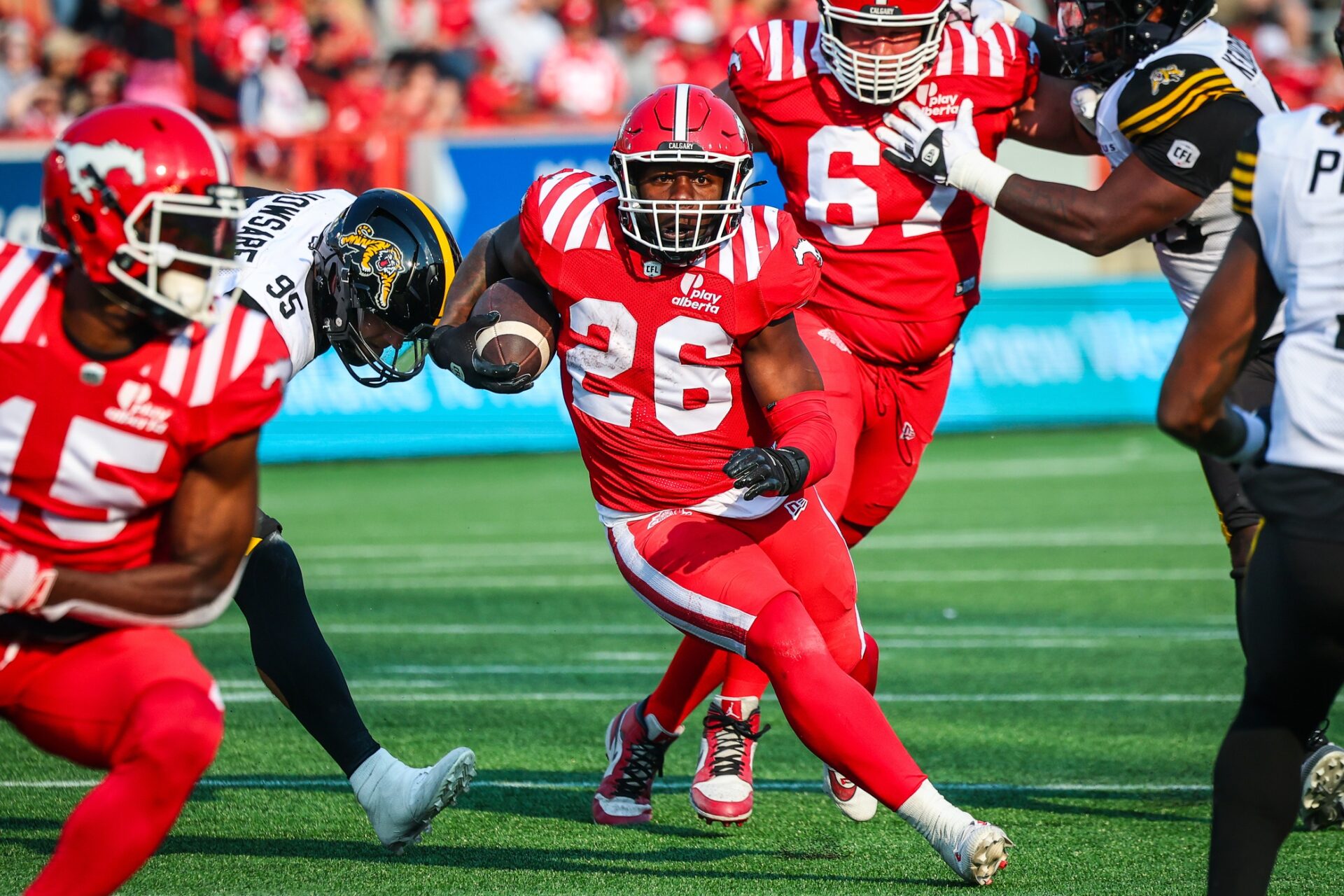 Jun 7, 2025; Calgary, Alberta, Canada; Calgary Stampeders running back Dedrick Mills (26) runs with the ball against the Hamilton Tiger-Cats during the second half at McMahon Stadium.