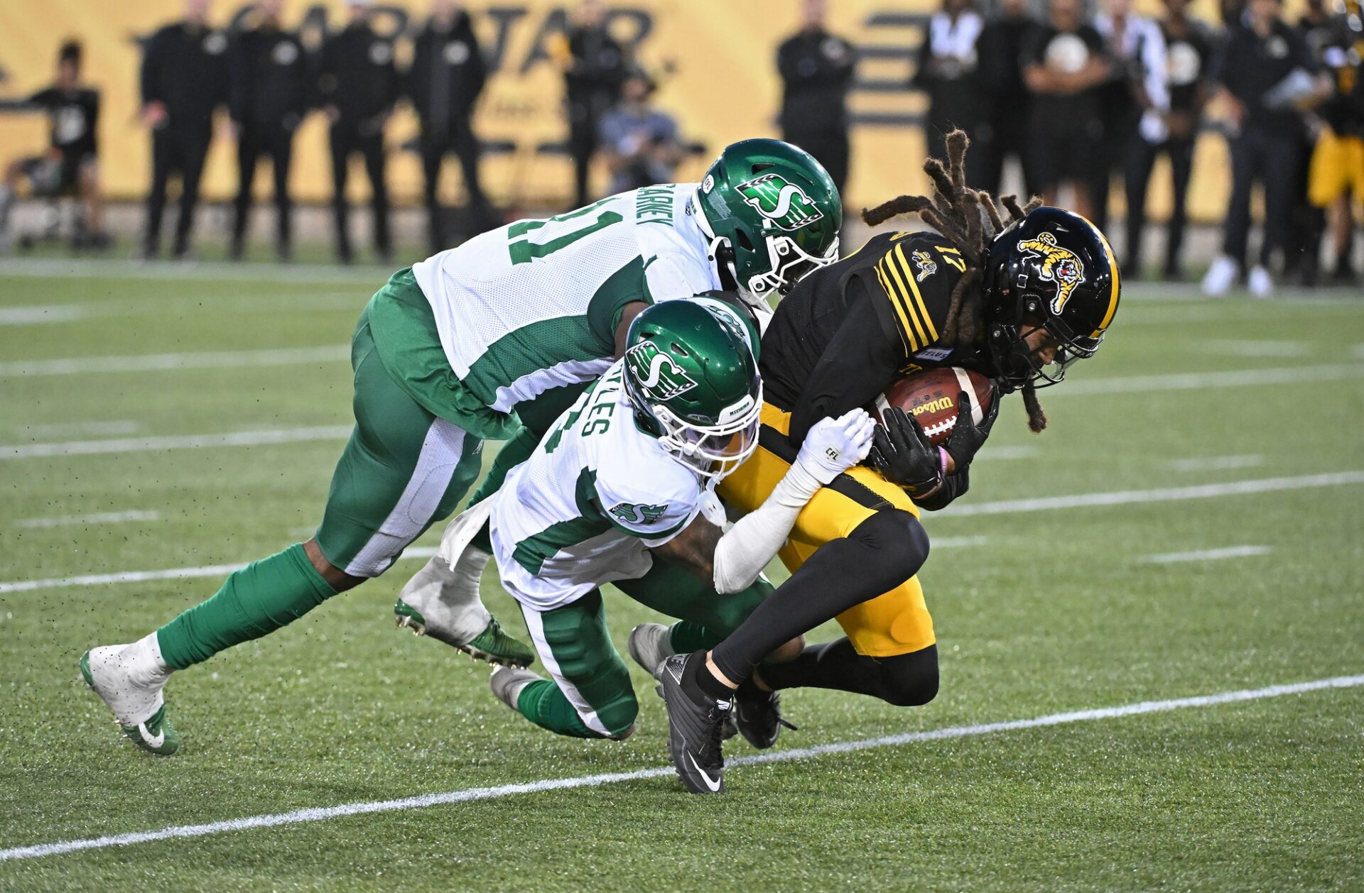 Jun 16, 2024; Hamilton, Ontario, CAN; Hamilton Tiger Cats wide receiver Shemar Bridges (17) is tackled by Saskatchewan Rough Riders defensive back Marcus Sayles (8) and defensive lineman Maalik Carney (11) in the third quarter at Tim Hortons Field.